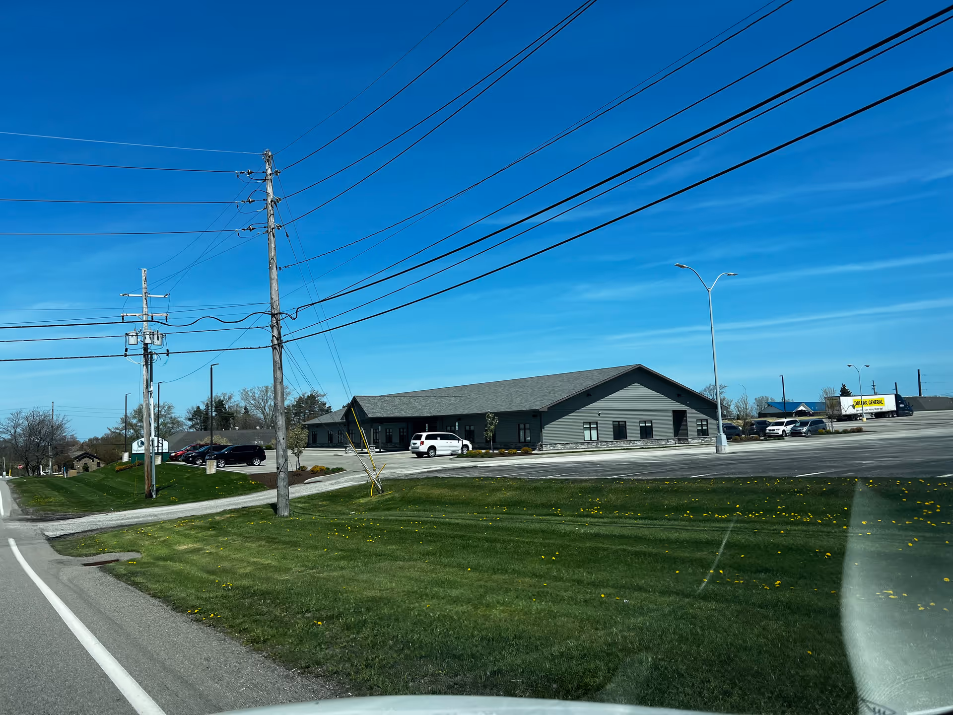 Wide exterior view of a single-story facility with a parking lot under a clear blue sky.