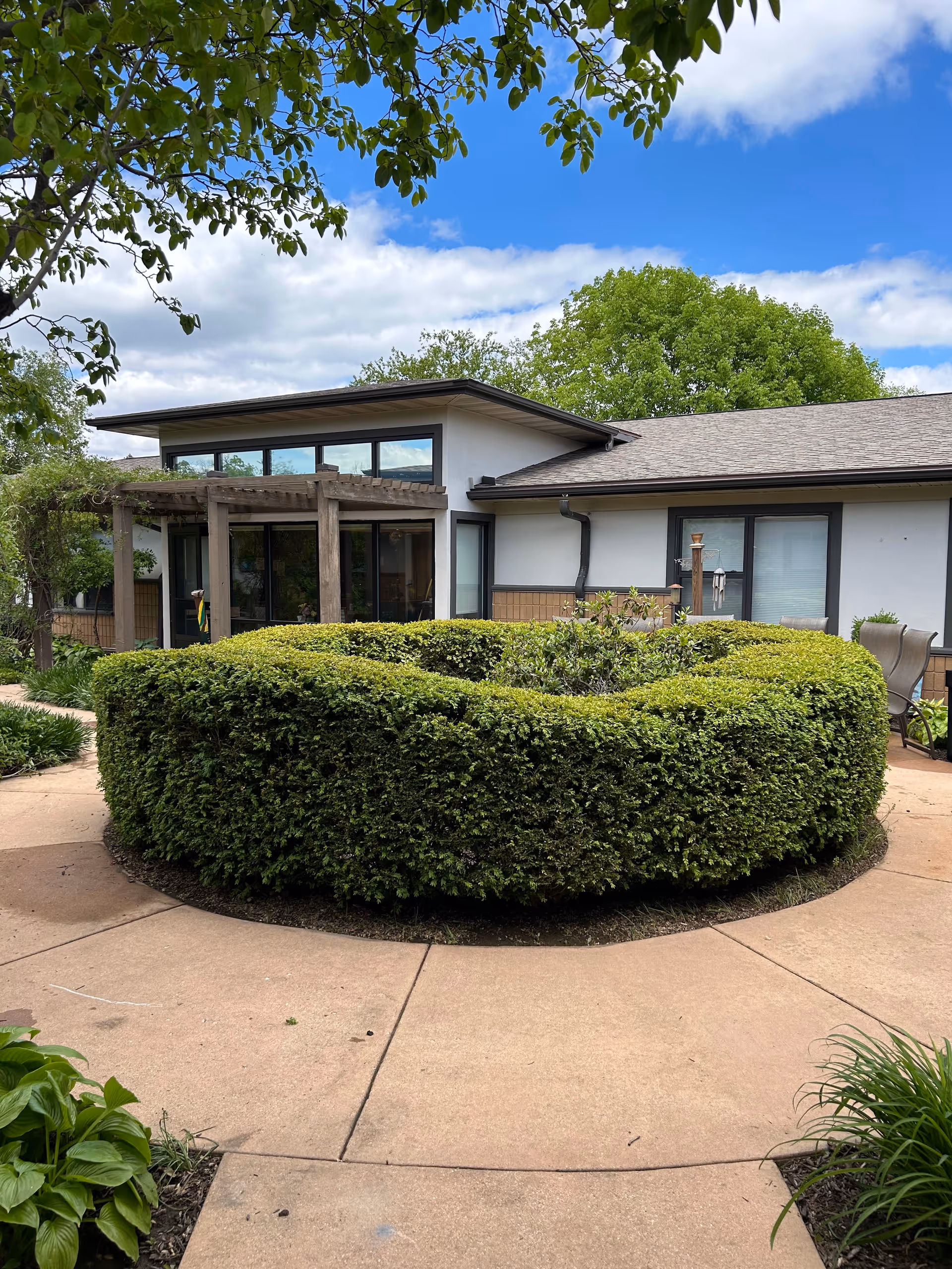 Exterior view of Oakwood Village University Woods with circular hedge, walkway, and modern façade.