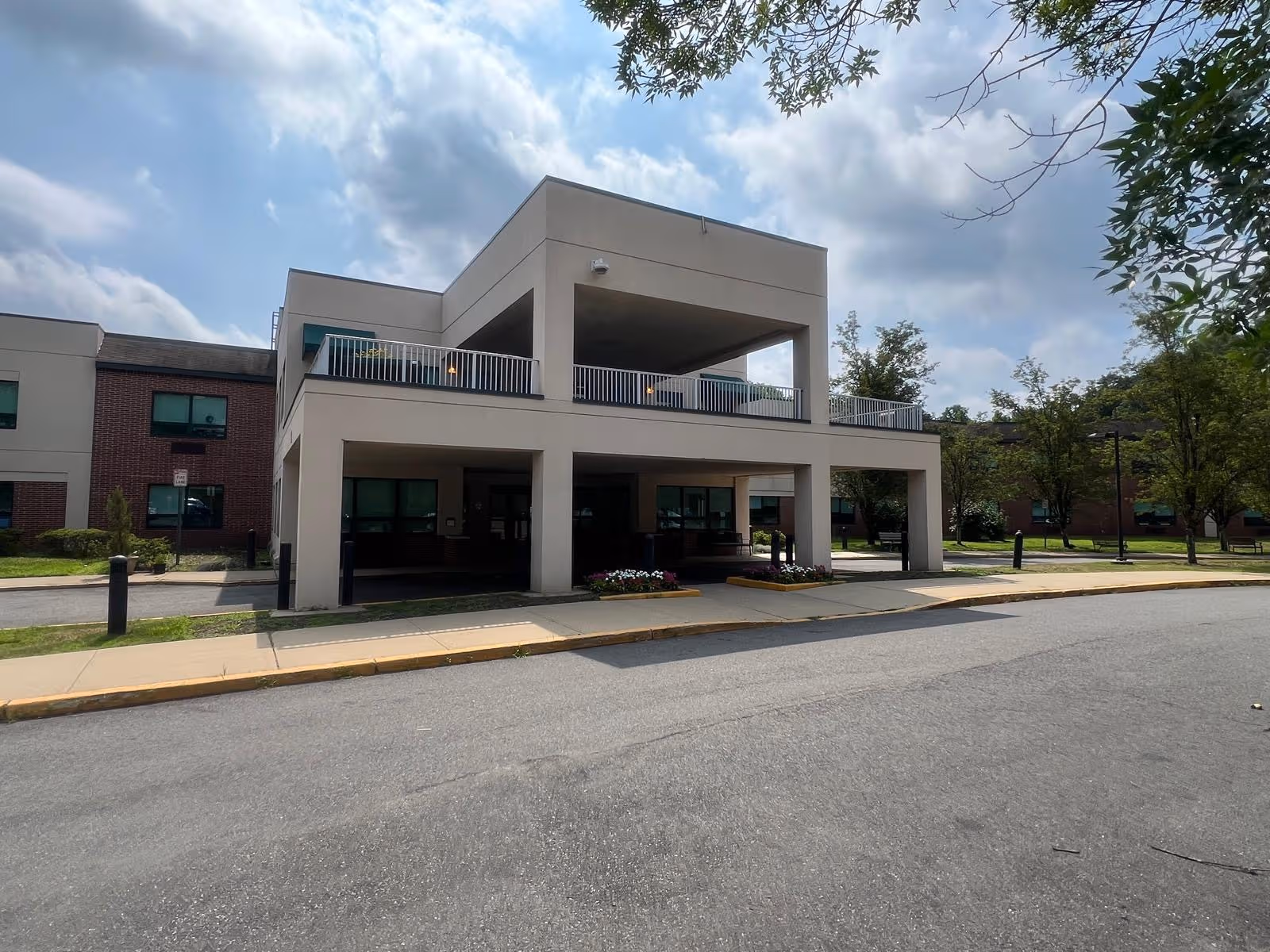 Modern two-story healthcare facility exterior with a covered entrance and drop-off area.