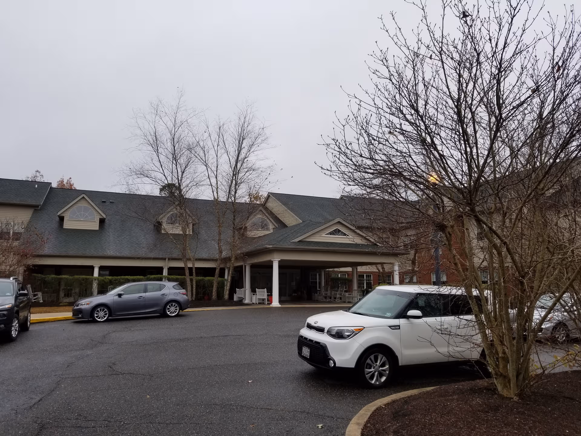 Exterior view of Woodview Estates senior living facility with a covered entrance and parked cars
