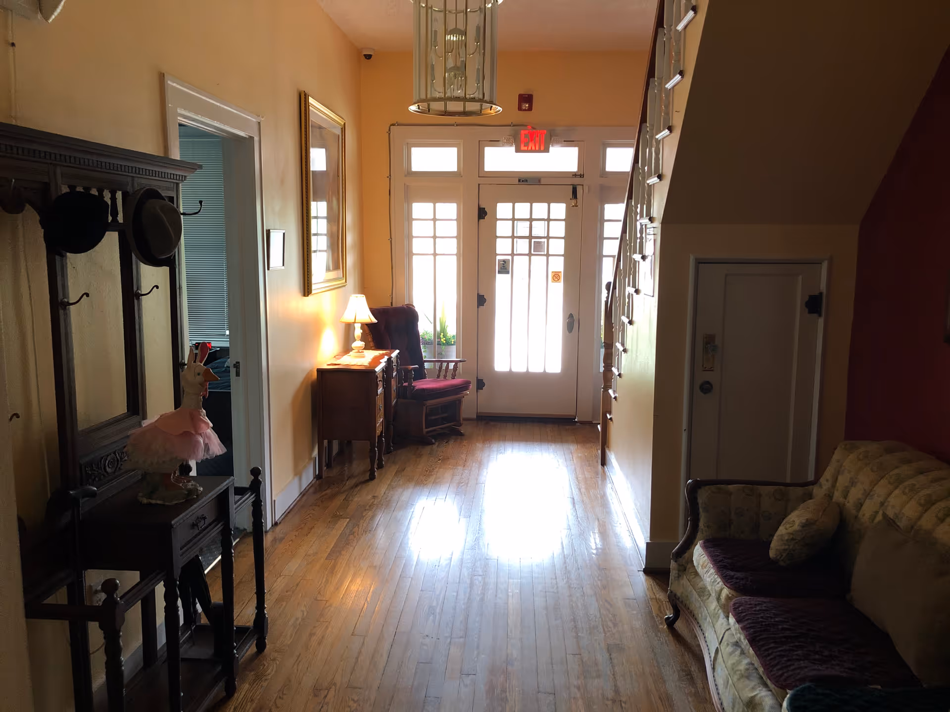 Cozy entry hall with wooden floors, furniture, and front door at the end.