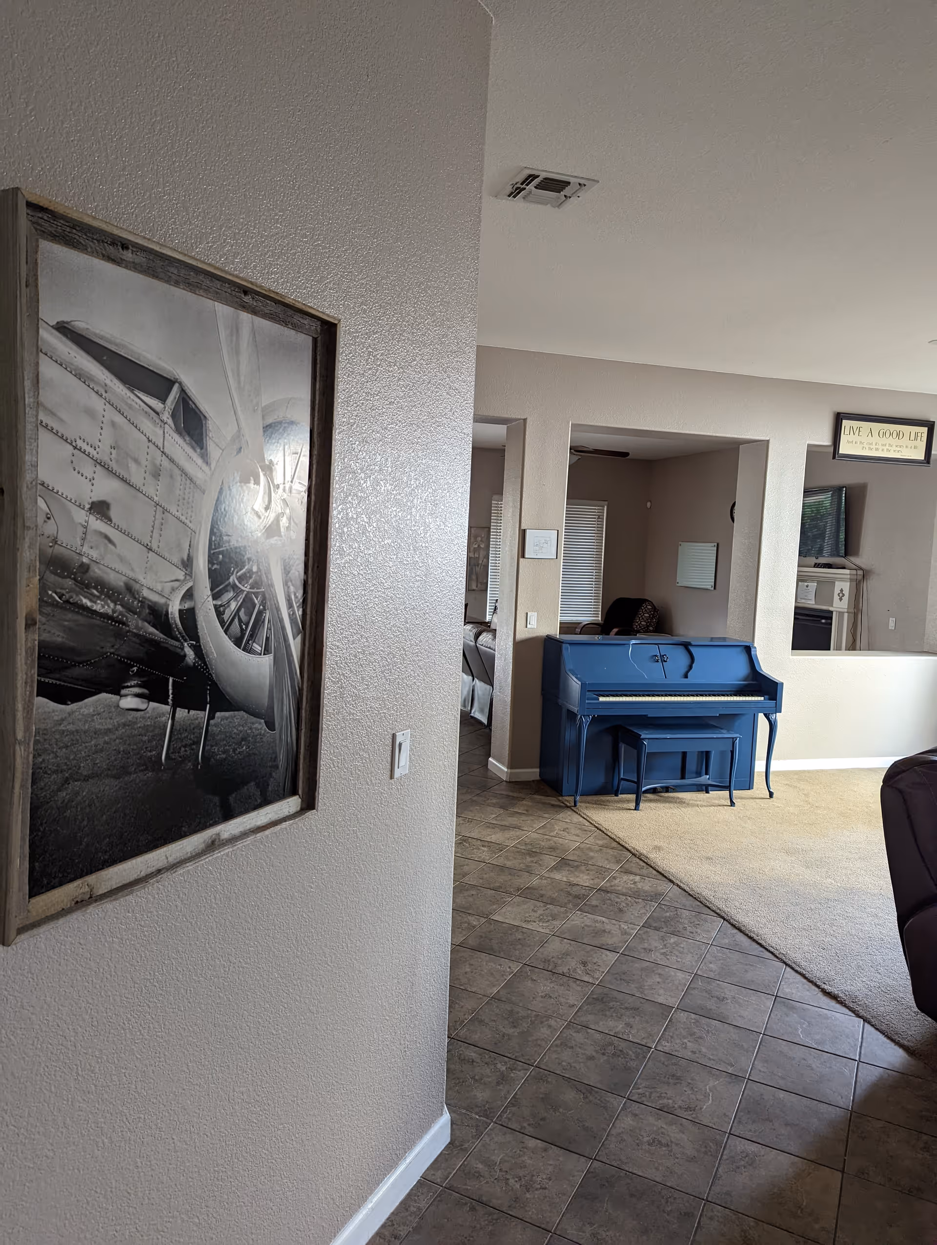 Blue piano in a spacious living area with adjacent hallways and wall art.