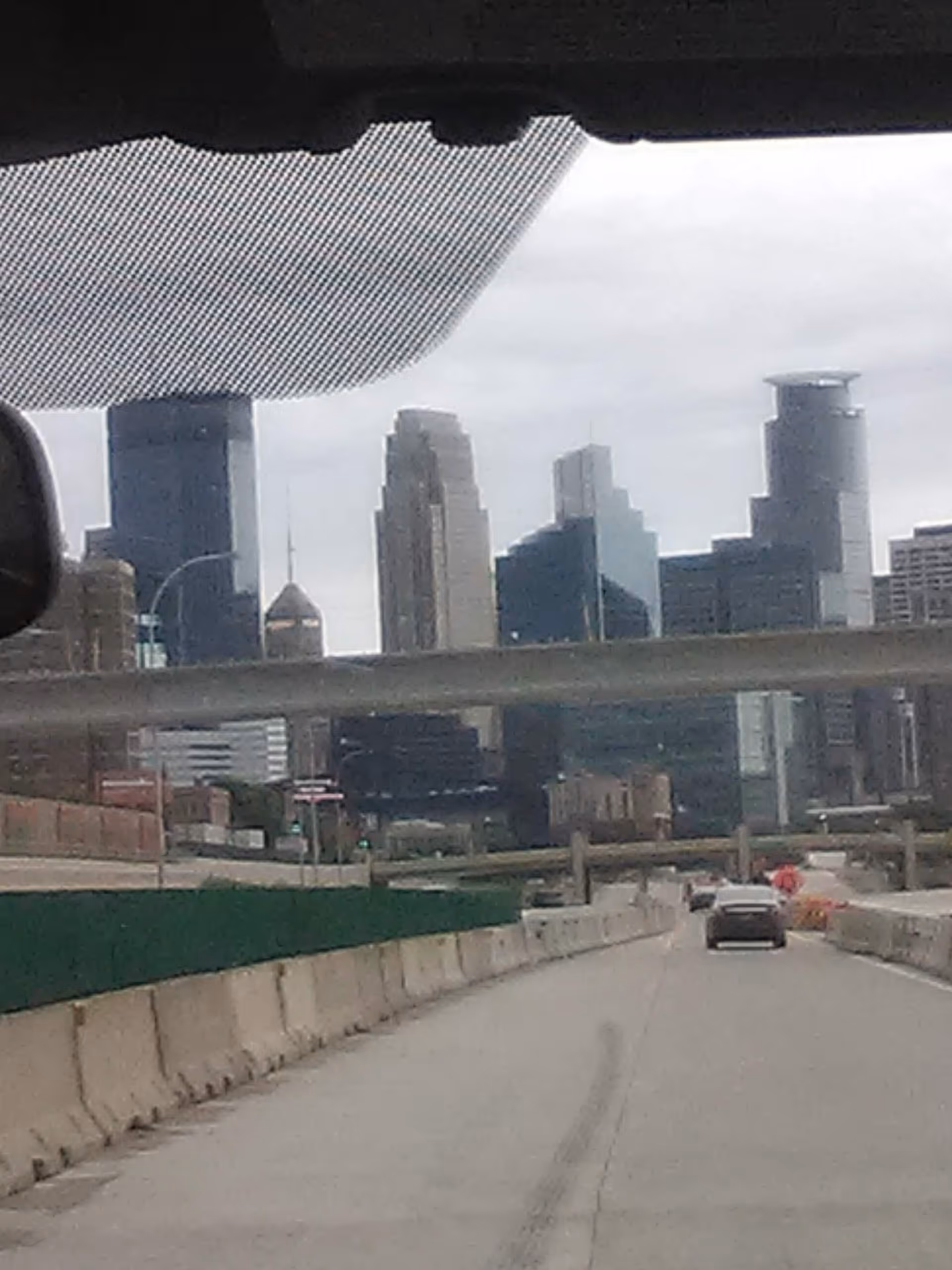 City skyline visible through car windshield on a highway.
