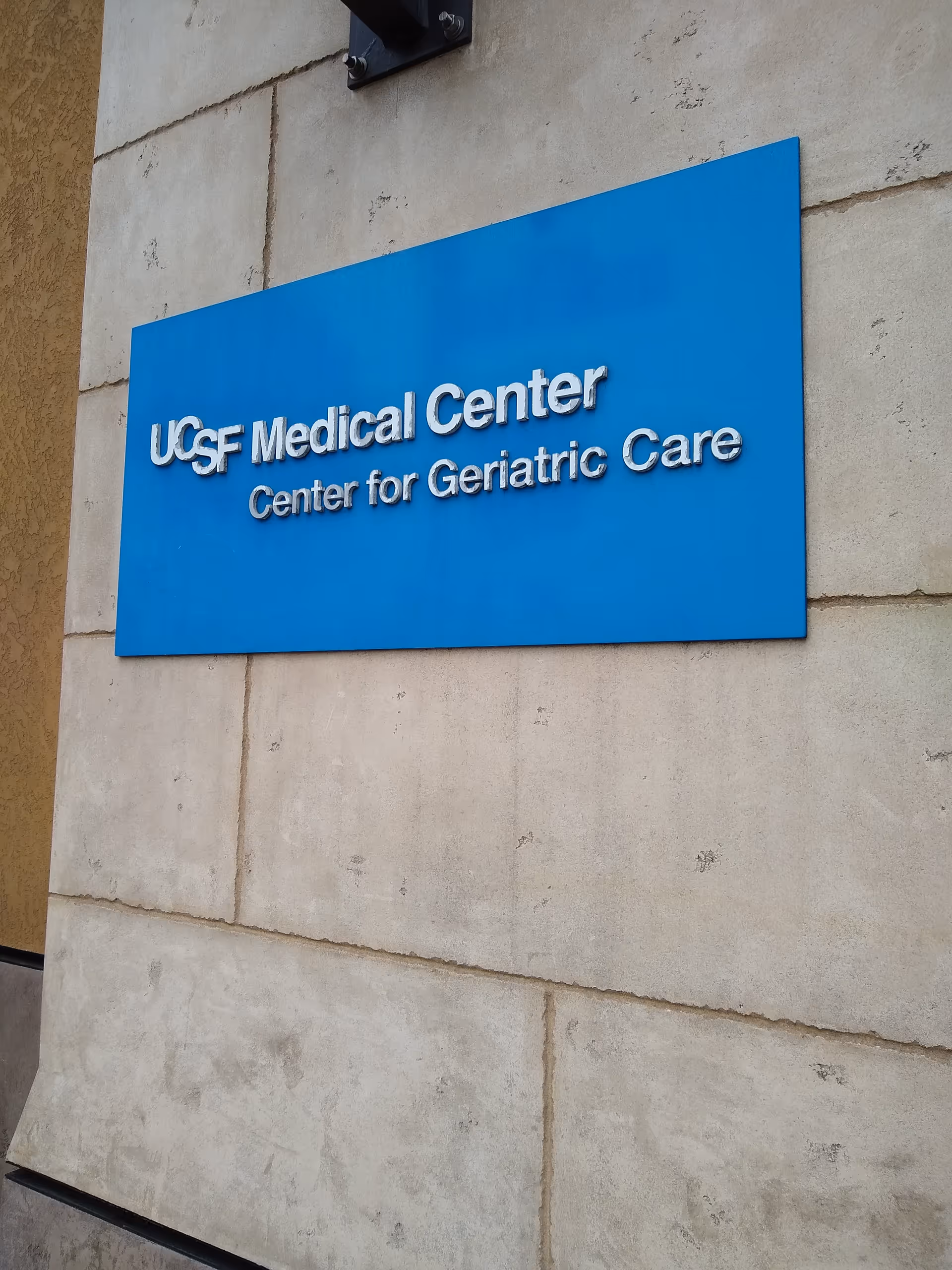 Blue sign on concrete wall reading 'USF Medical Center Center for Geriatric Care'.