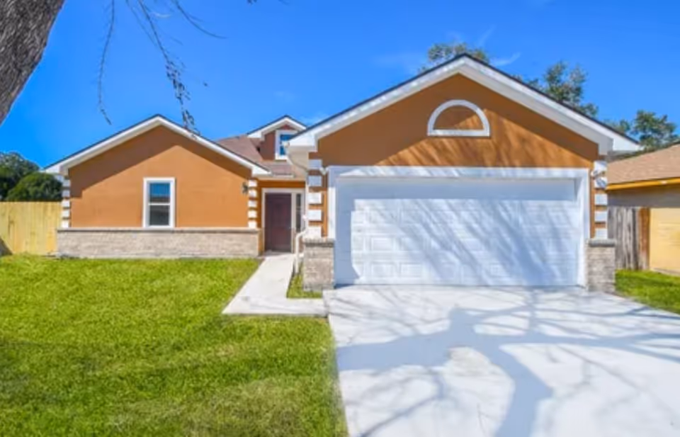 Front view of an orange single-story house with a white two-car garage door.
