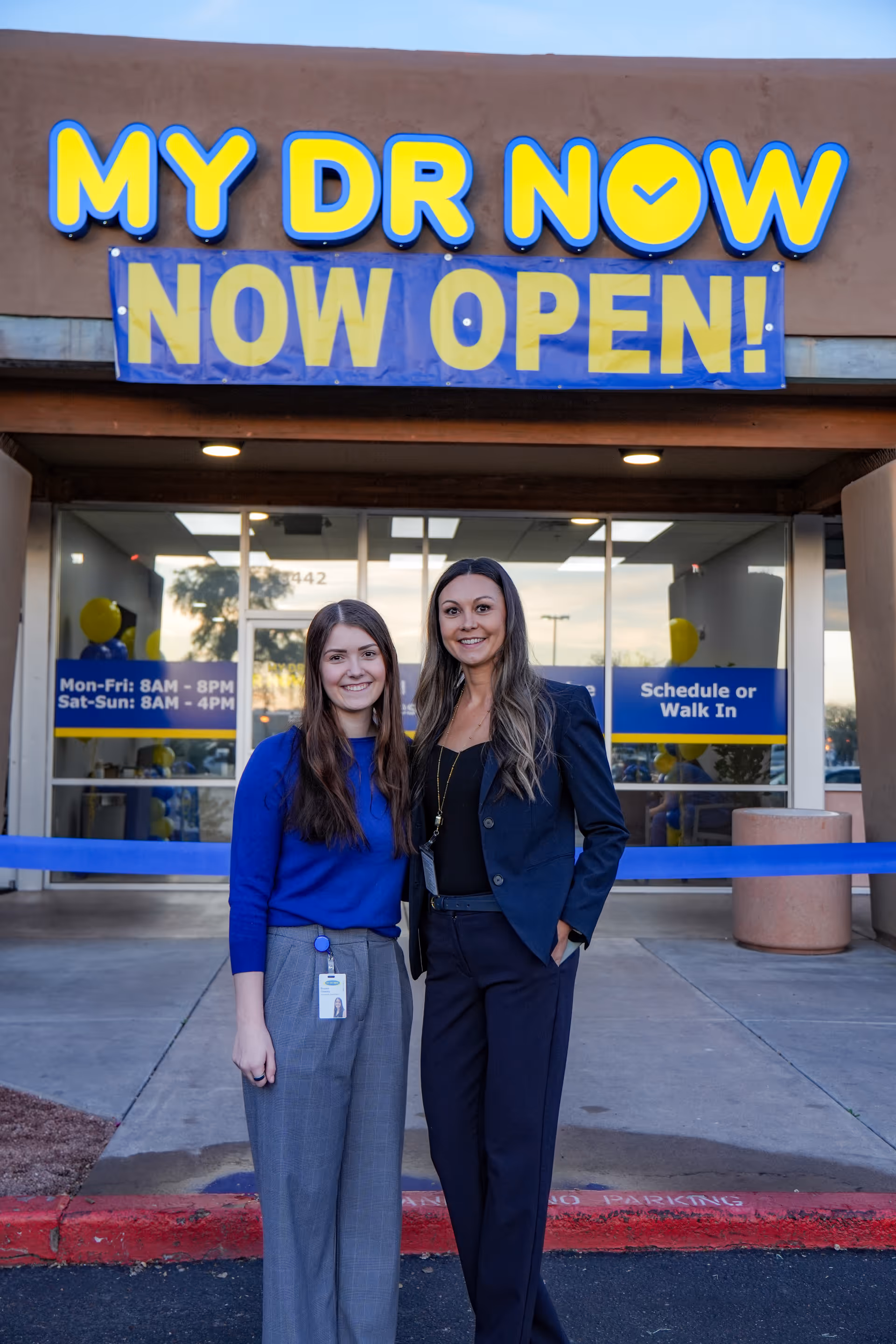 Two women stand outside a storefront with a large 'MY DR NOW' and 'NOW OPEN' sign.