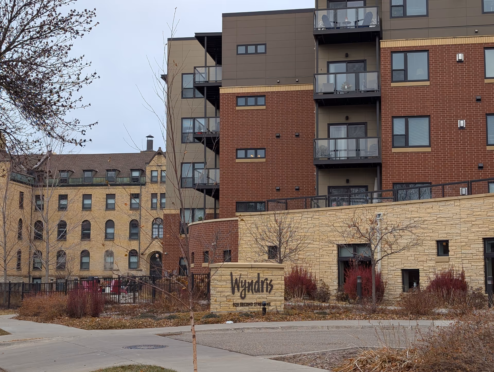Exterior view of the Wyndris senior living building with a stone entrance sign, balconies, and landscaped front.