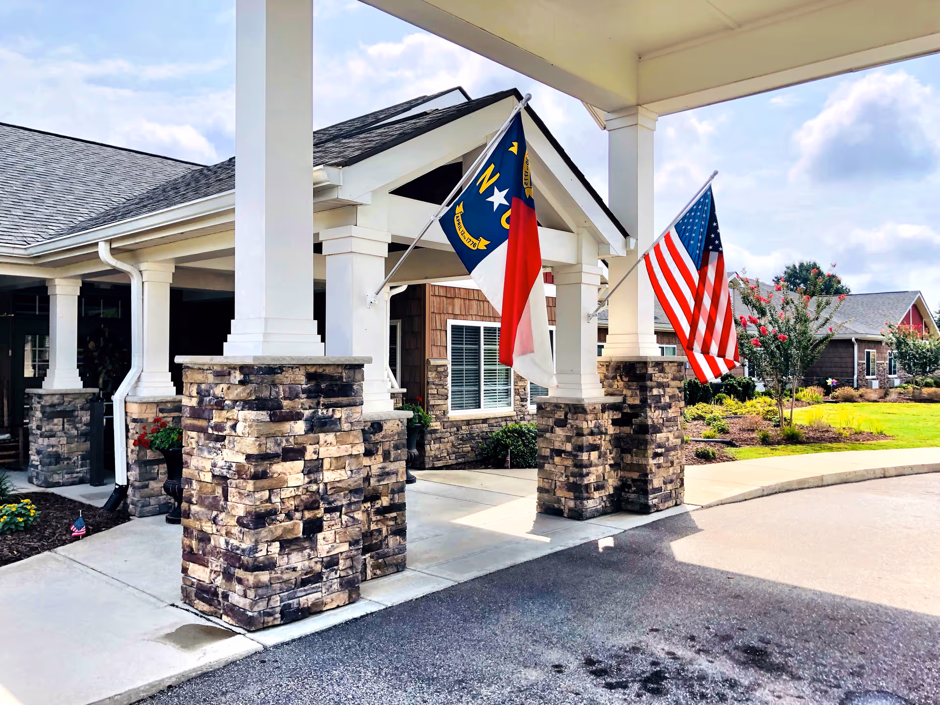Front entrance of Gabriel Manor Assisted Living Center with stone columns and flags.