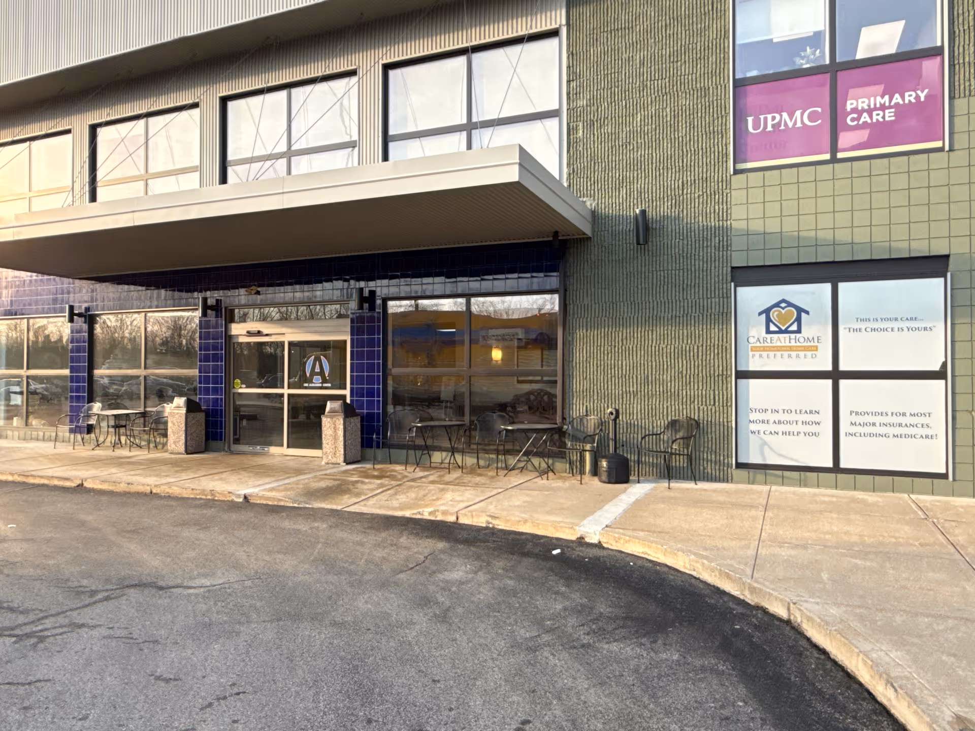 Exterior view of Care At Home Preferred facility with glass doors and outdoor seating.