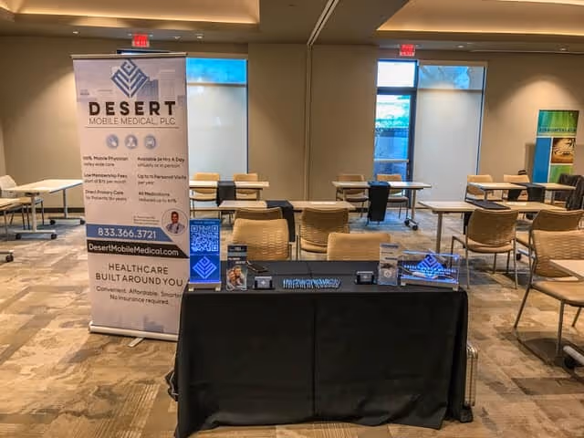 Indoor conference room with Desert Mobile Medical banner and arranged seating.