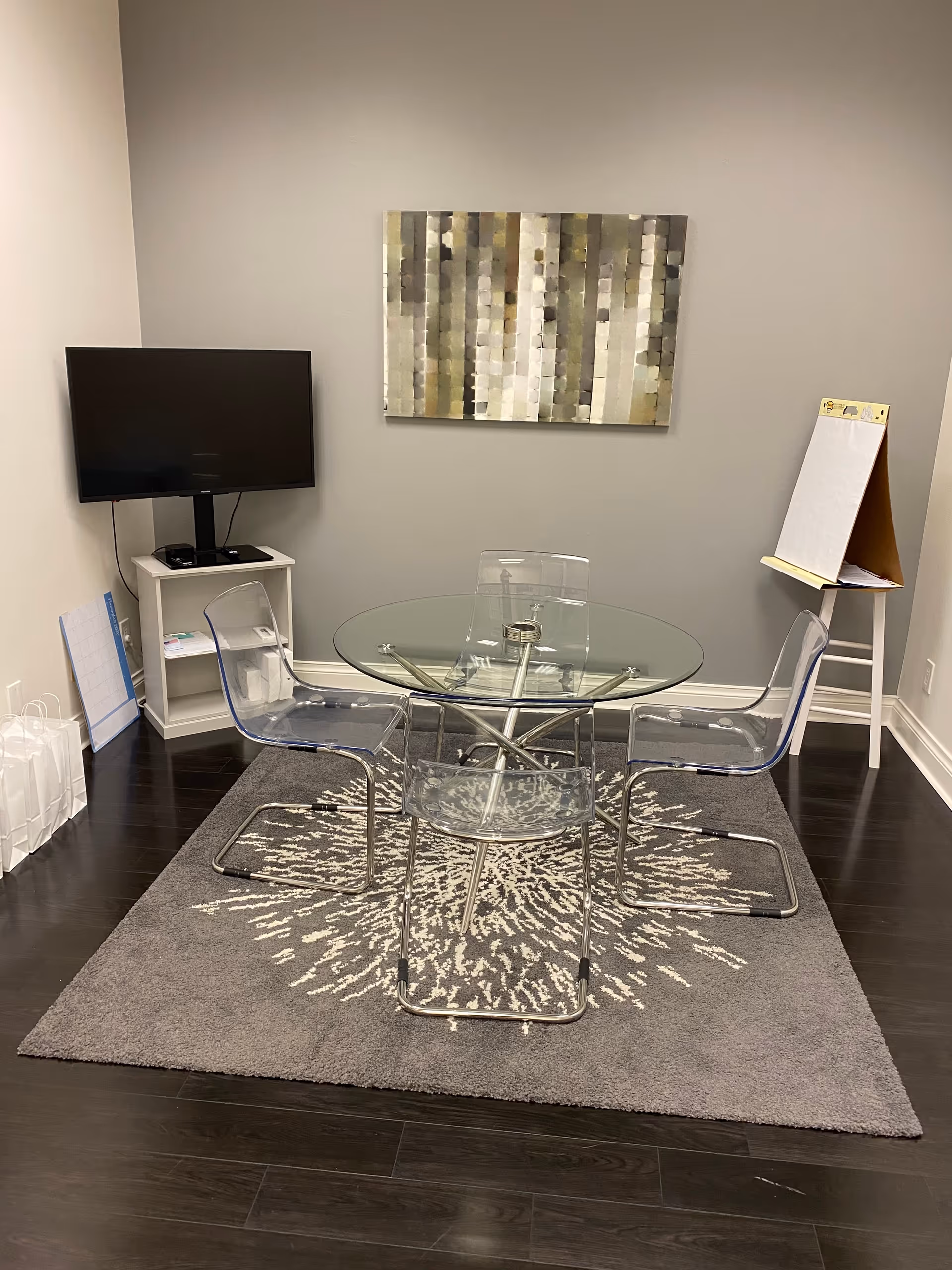 Glass round table with four clear chairs in a small contemporary dining area.