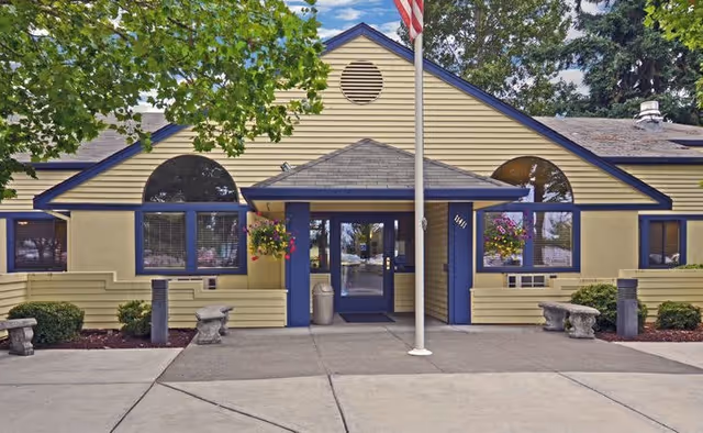The Oaks At Lakewood exterior featuring a yellow building with blue trim and a front entrance.