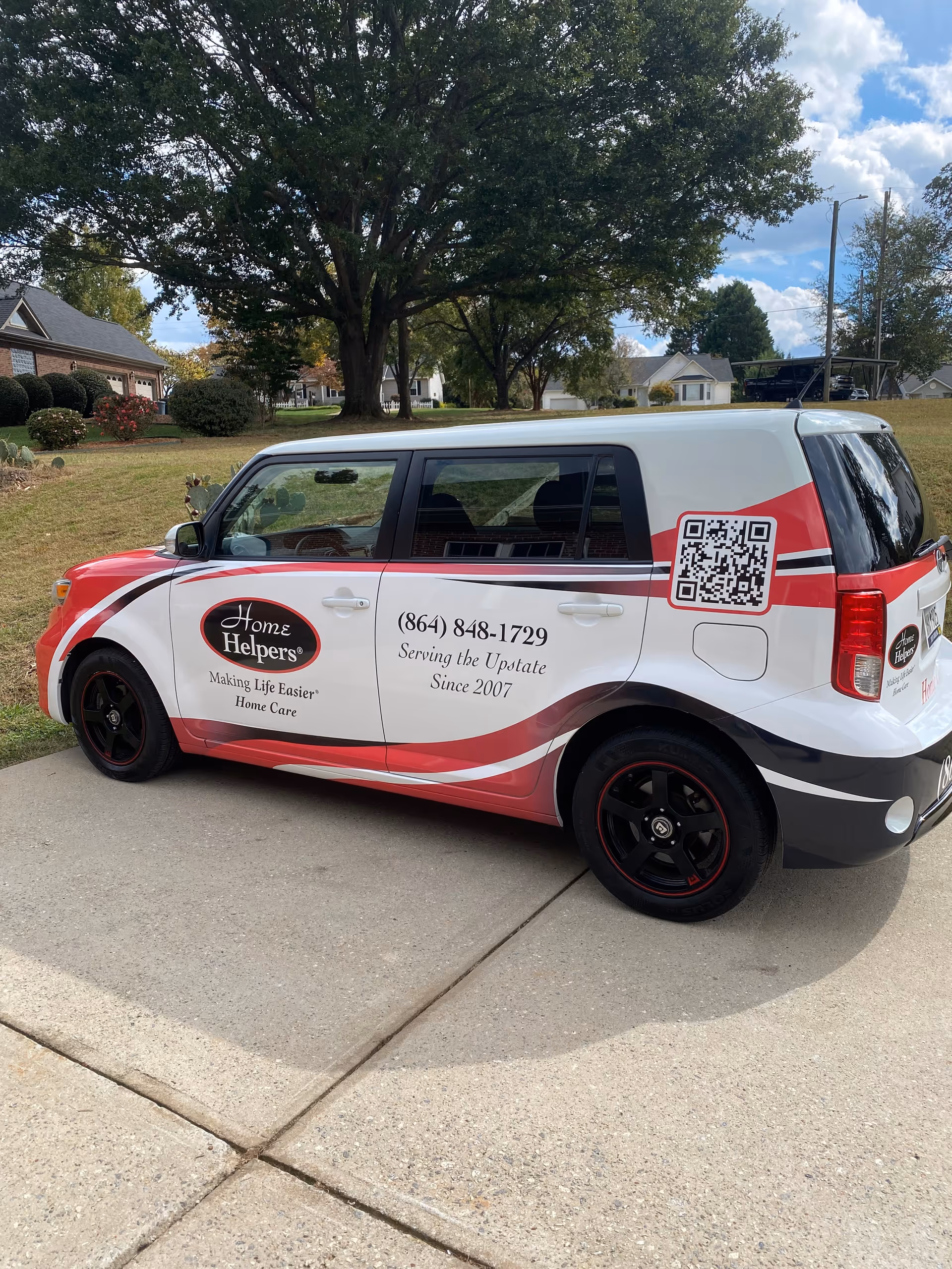 Branded Home Helpers Home Care van parked on a suburban street with trees and houses.