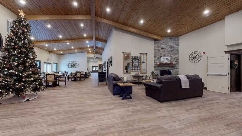 Spacious living room in a senior facility with a Christmas tree, fireplace, and seating.