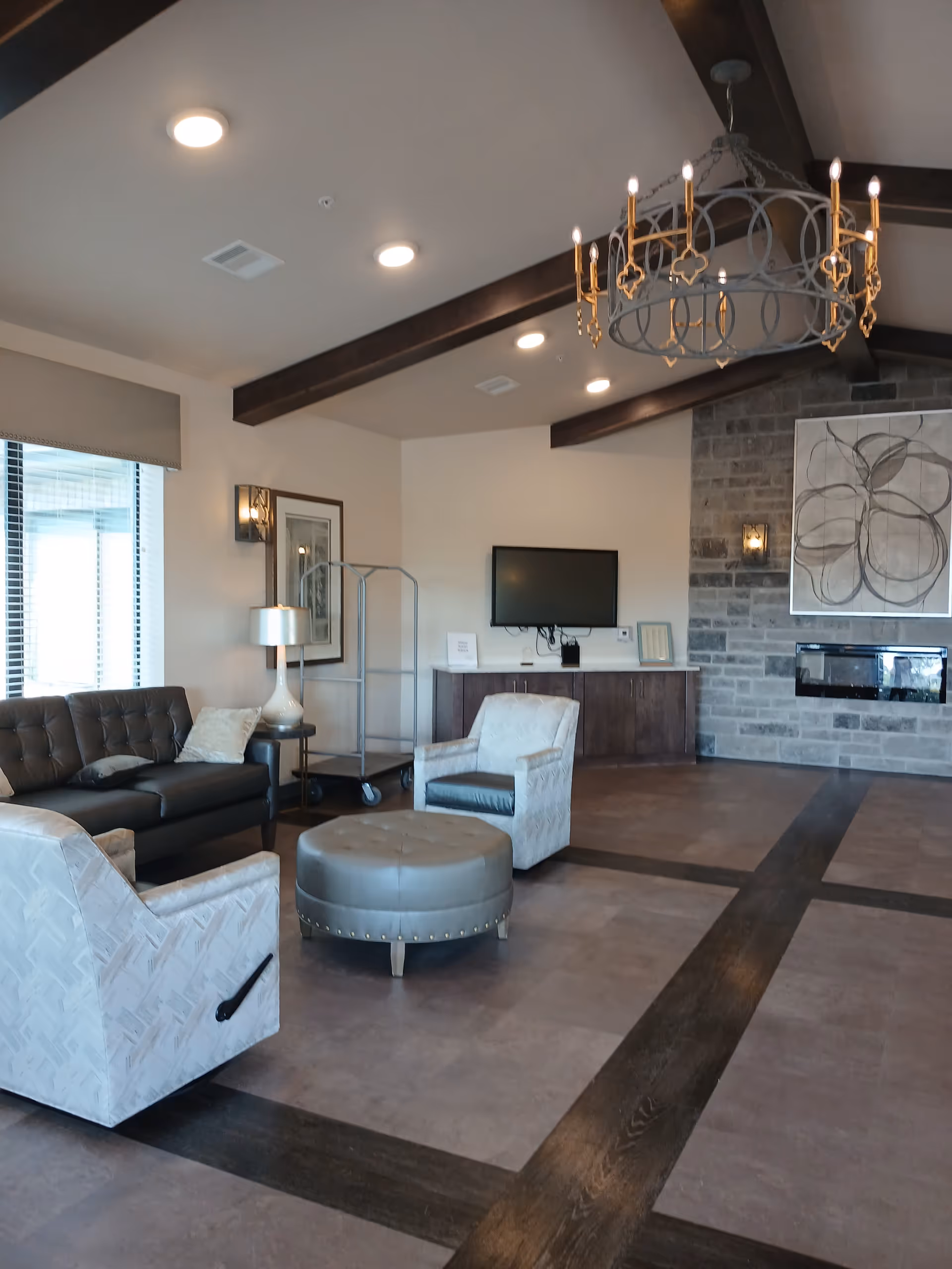 Spacious senior living lobby with couch, chairs, ottoman, chandelier, TV, and fireplace.