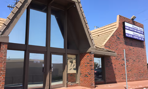Front exterior of a brick building with glass doors and a hospice care sign.