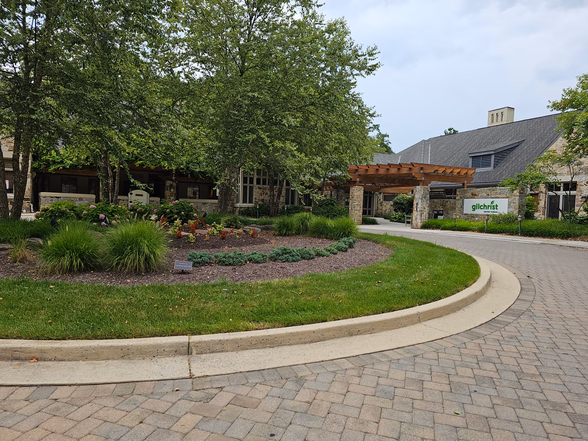 Curved brick driveway leads to the Gilchrist Center Towson entrance surrounded by greenery.