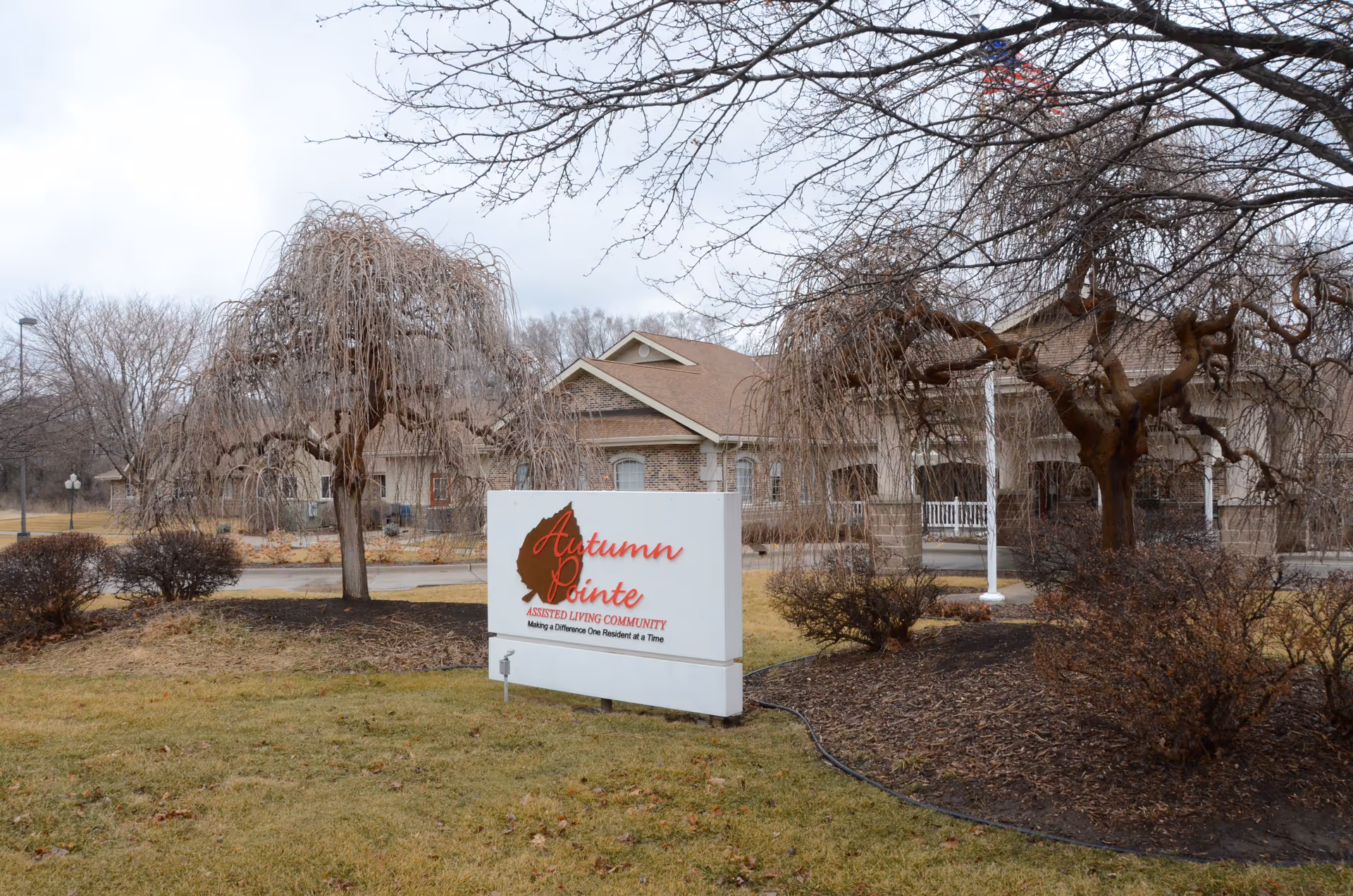 Exterior view of Autumn Pointe Assisted Living with a front sign and leafless trees.