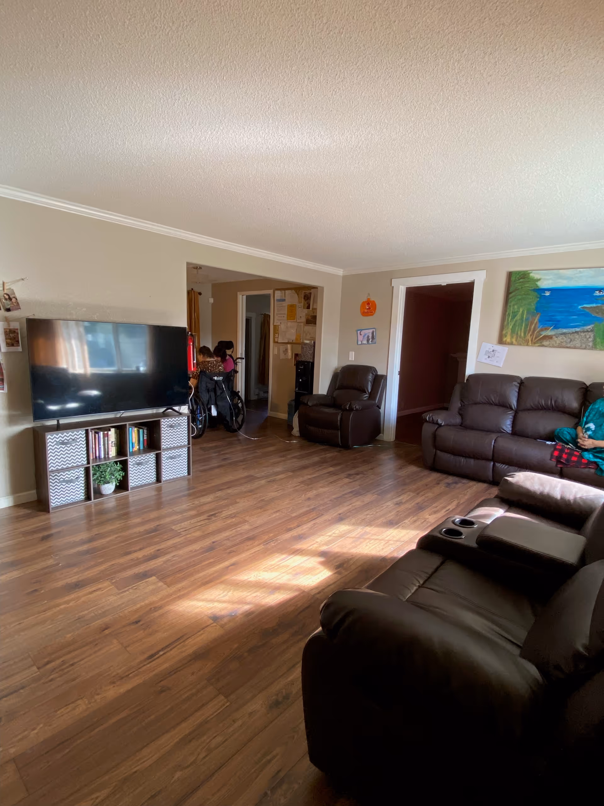 Spacious living room with brown leather sofas, TV, and wooden floor.