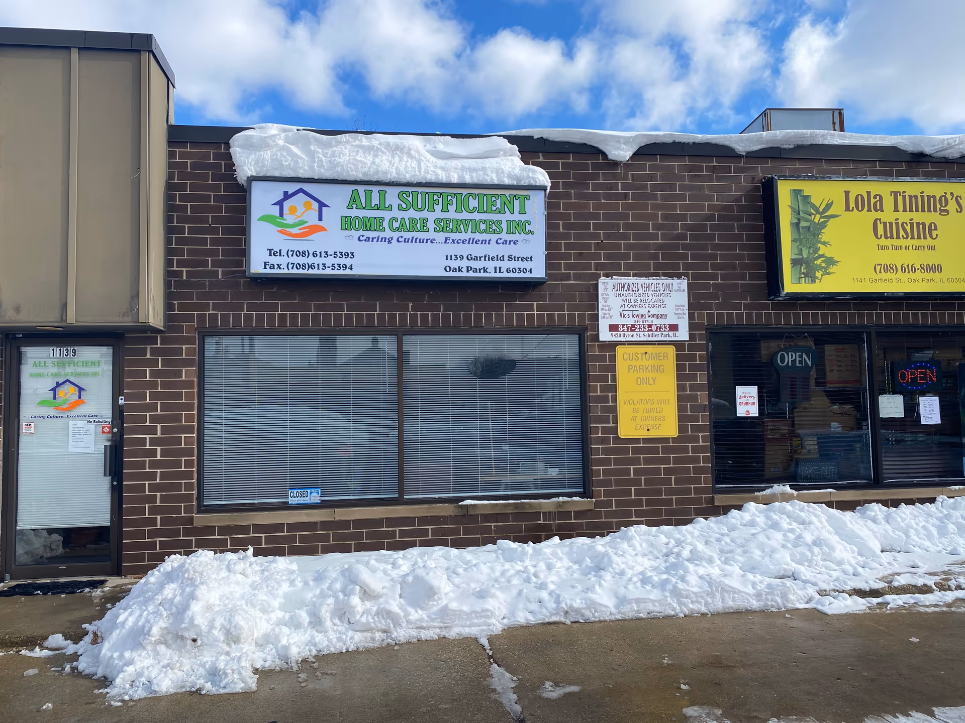 Front exterior of a brick building with All Sufficient Home Care Services sign and snow