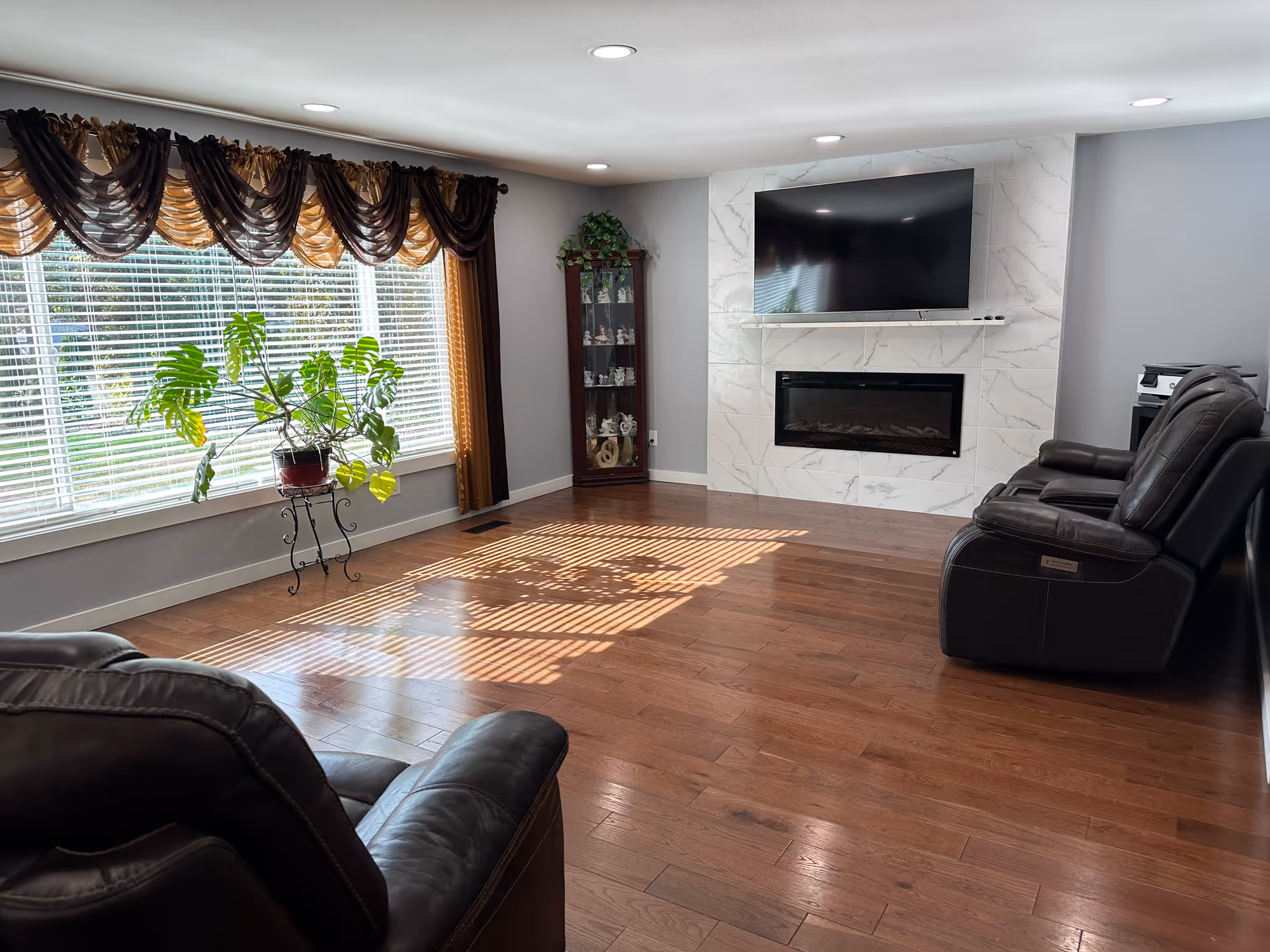 Bright Harmony Lane living room with leather recliners, large windows, fireplace, and TV.