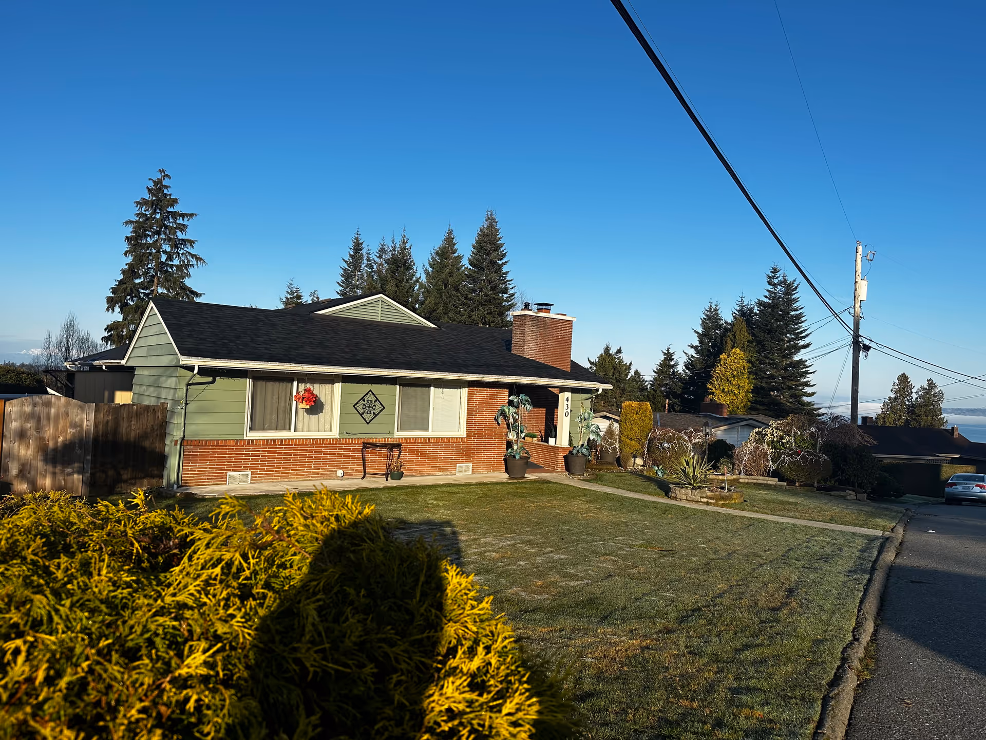 A single-story house with brick base, green siding, and a tidy front yard.