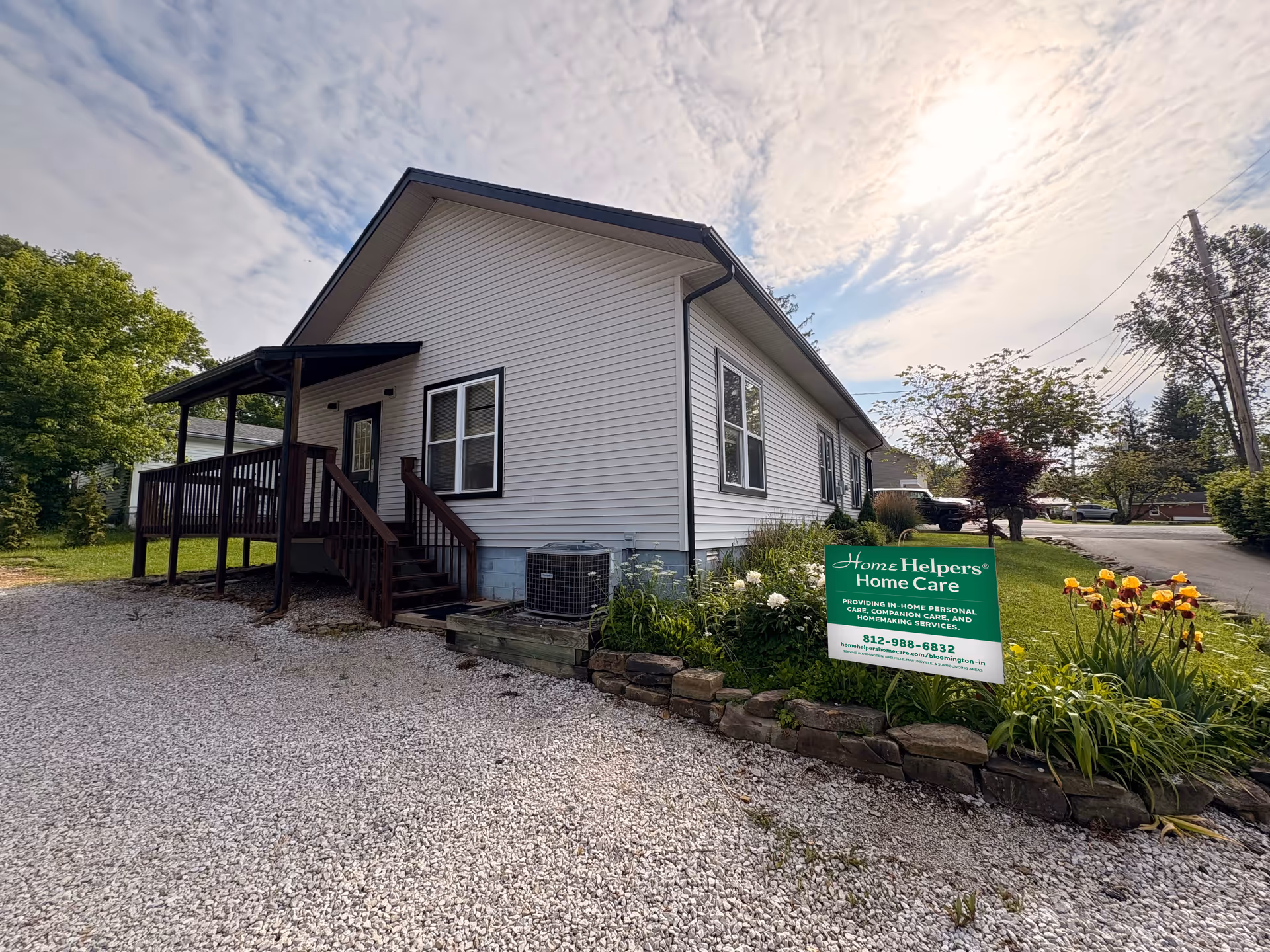 White, single-story building with a dark porch and a green Home Helpers sign.