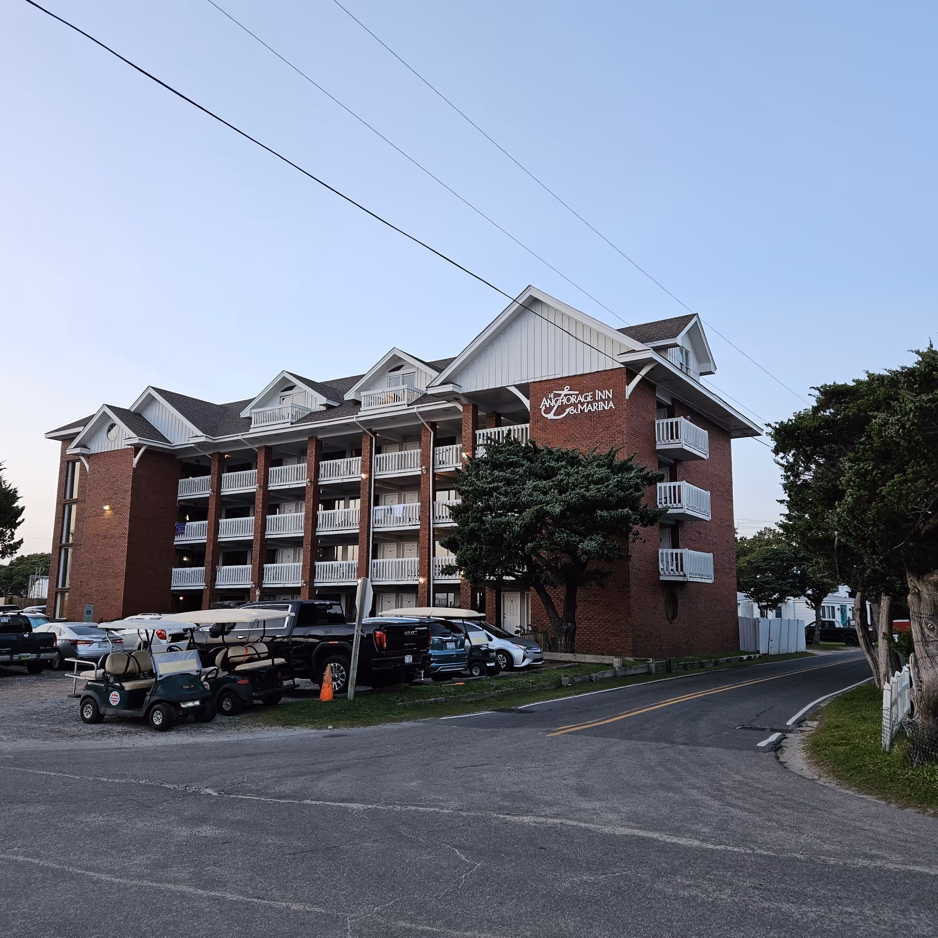 Exterior view of a brick multi-story senior living building with balconies and parked cars.