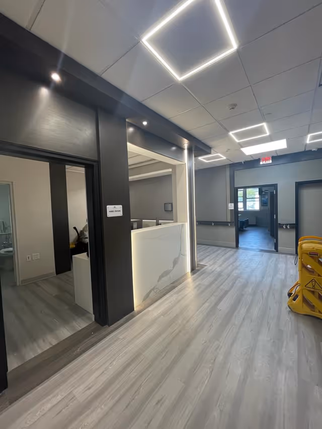 Modern reception desk and bright lobby hallway inside Teaneck Nursing Center.