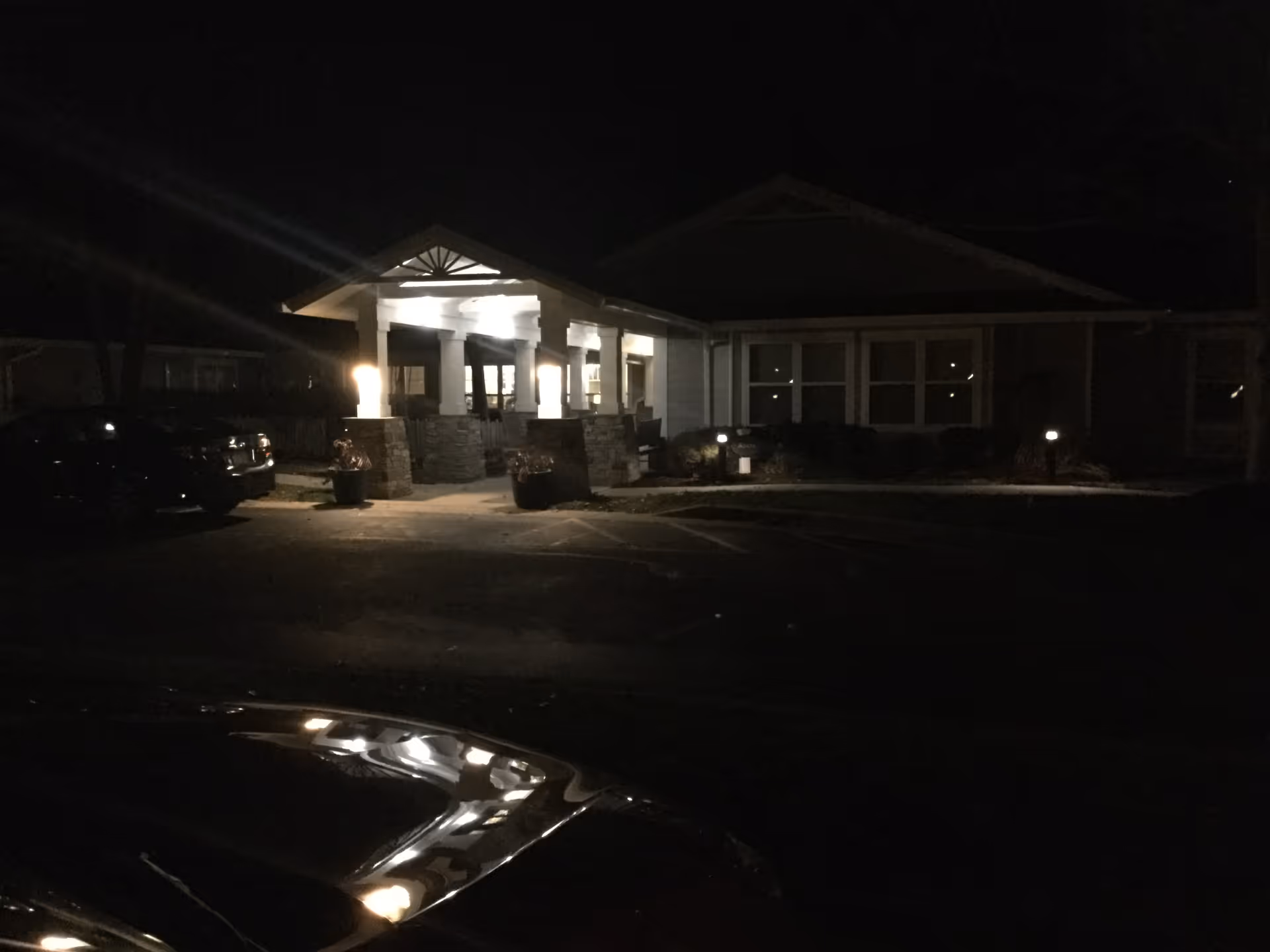 Night view of Sunrise of Richmond entrance with lit columns and parked cars.