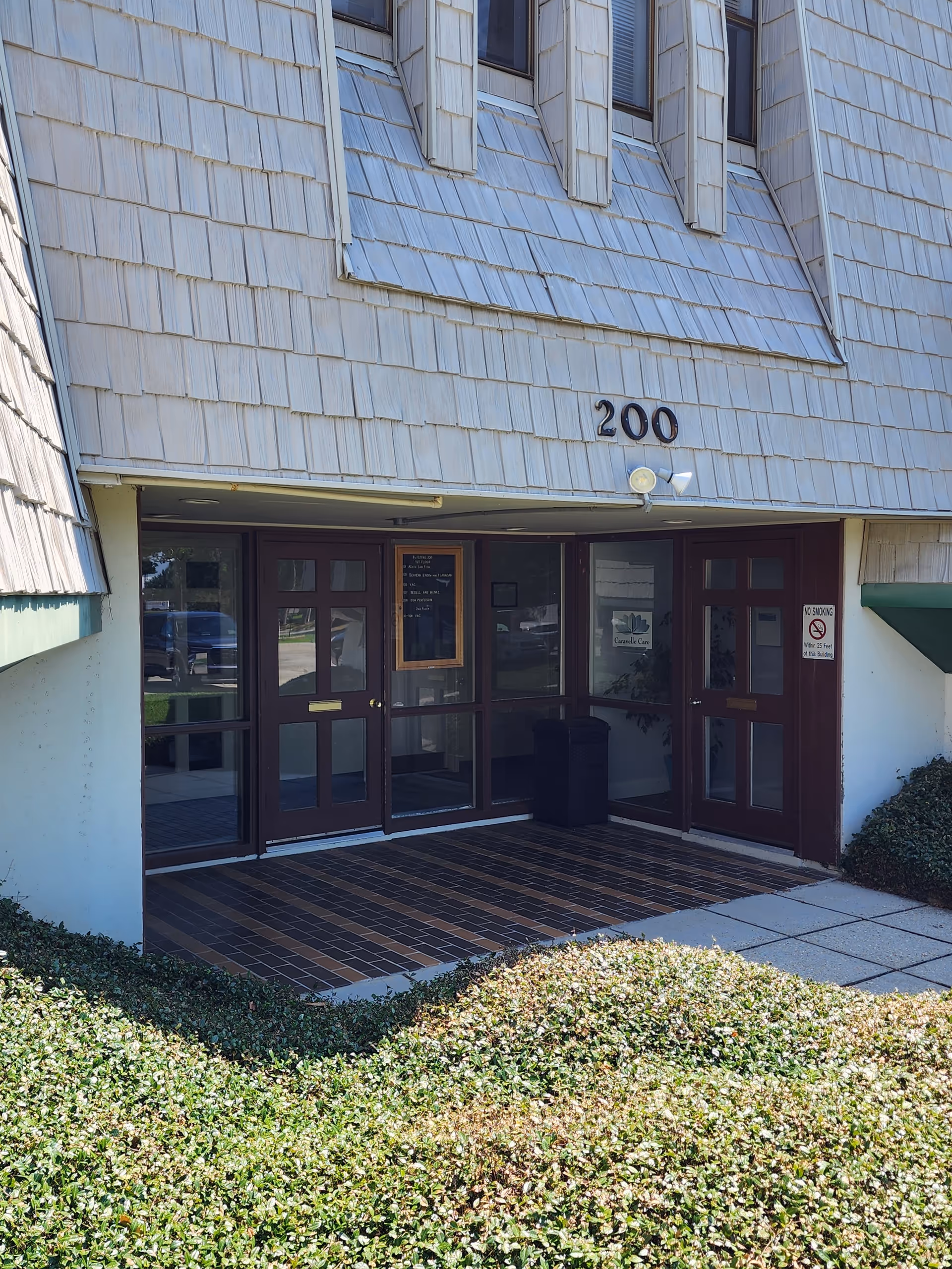 Exterior entrance to Caravelle Care with double doors and shrubs.
