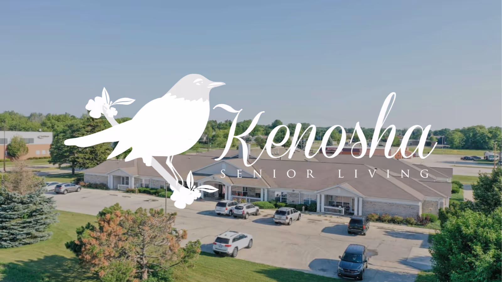 Front view of Kenosha Senior Living facility with parking and surrounding greenery.