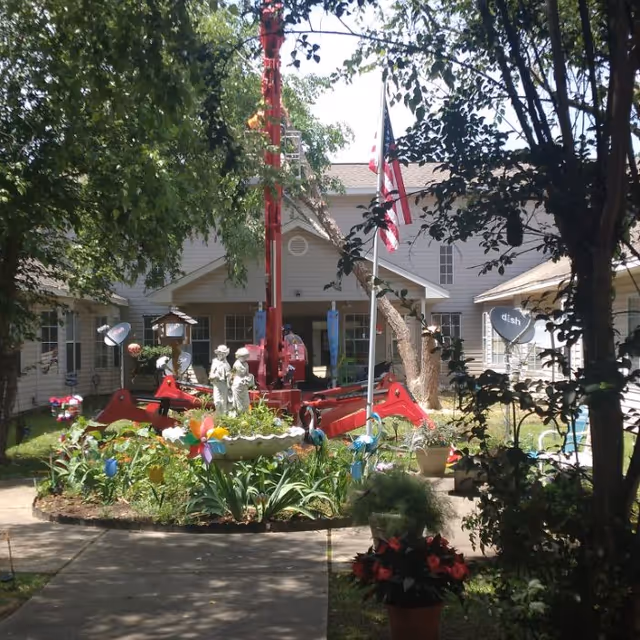 Outdoor courtyard of Davis Elderly Care with colorful garden, statue fountain, and flags