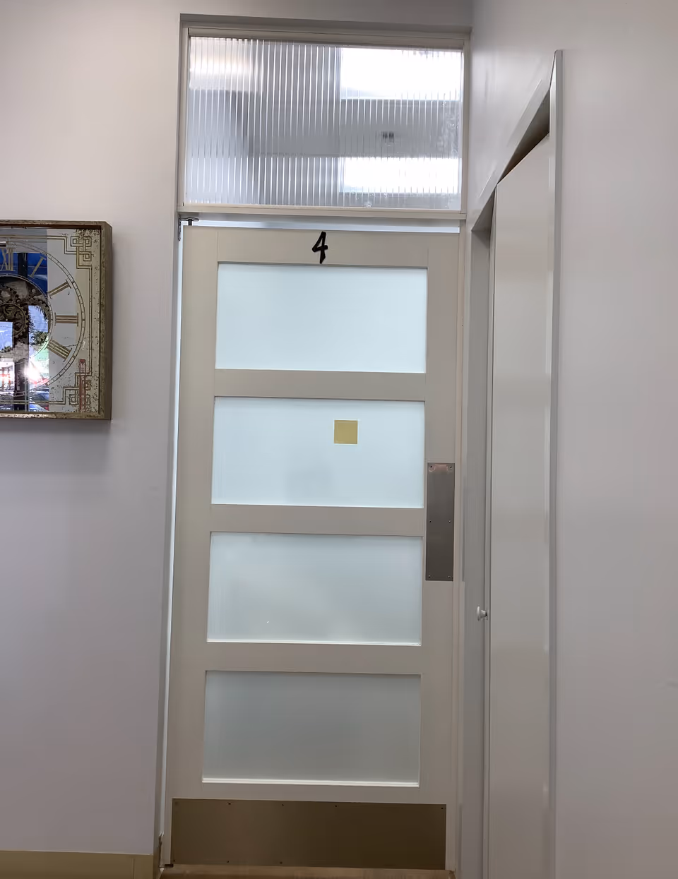 White frosted-glass door labeled 4 in a bright, empty hallway.