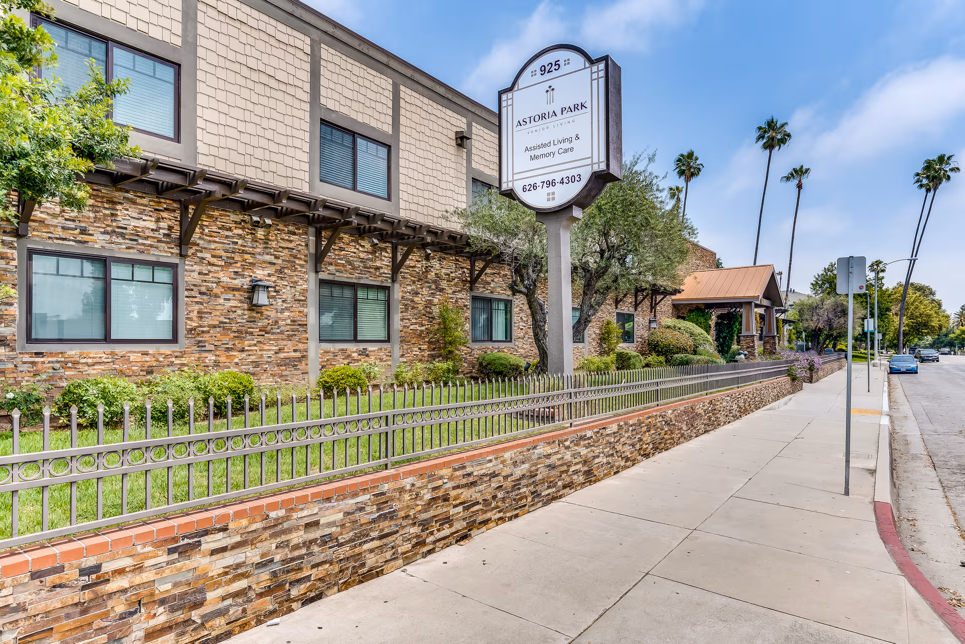 Exterior view of Astoria Park Senior Living building with sign, sidewalk, and landscaping.