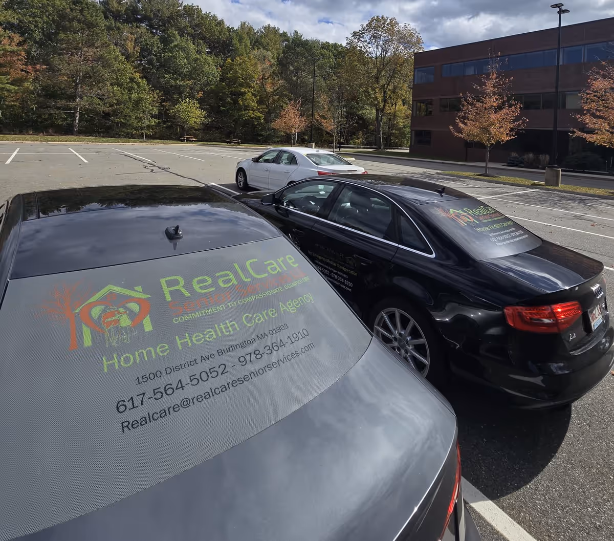 Parking lot with branded vehicles near a brick office building.
