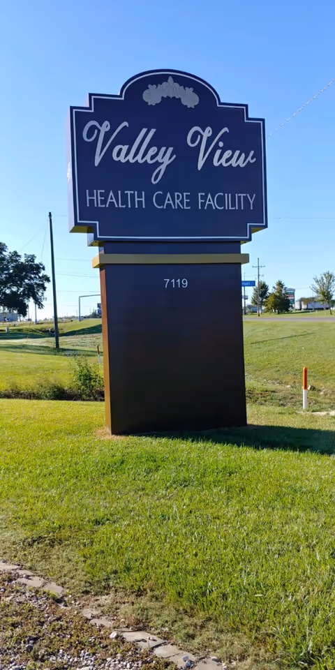 Blue Valley View Health Care Facility sign on a grassy front lawn beside the road.