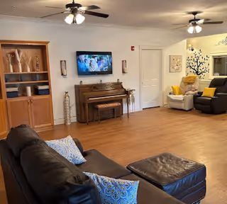 Spacious living area with a leather sofa, piano, TV, and cozy seating.