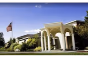 Exterior view of Country Pines Retirement Community with white arched entrance and flag.