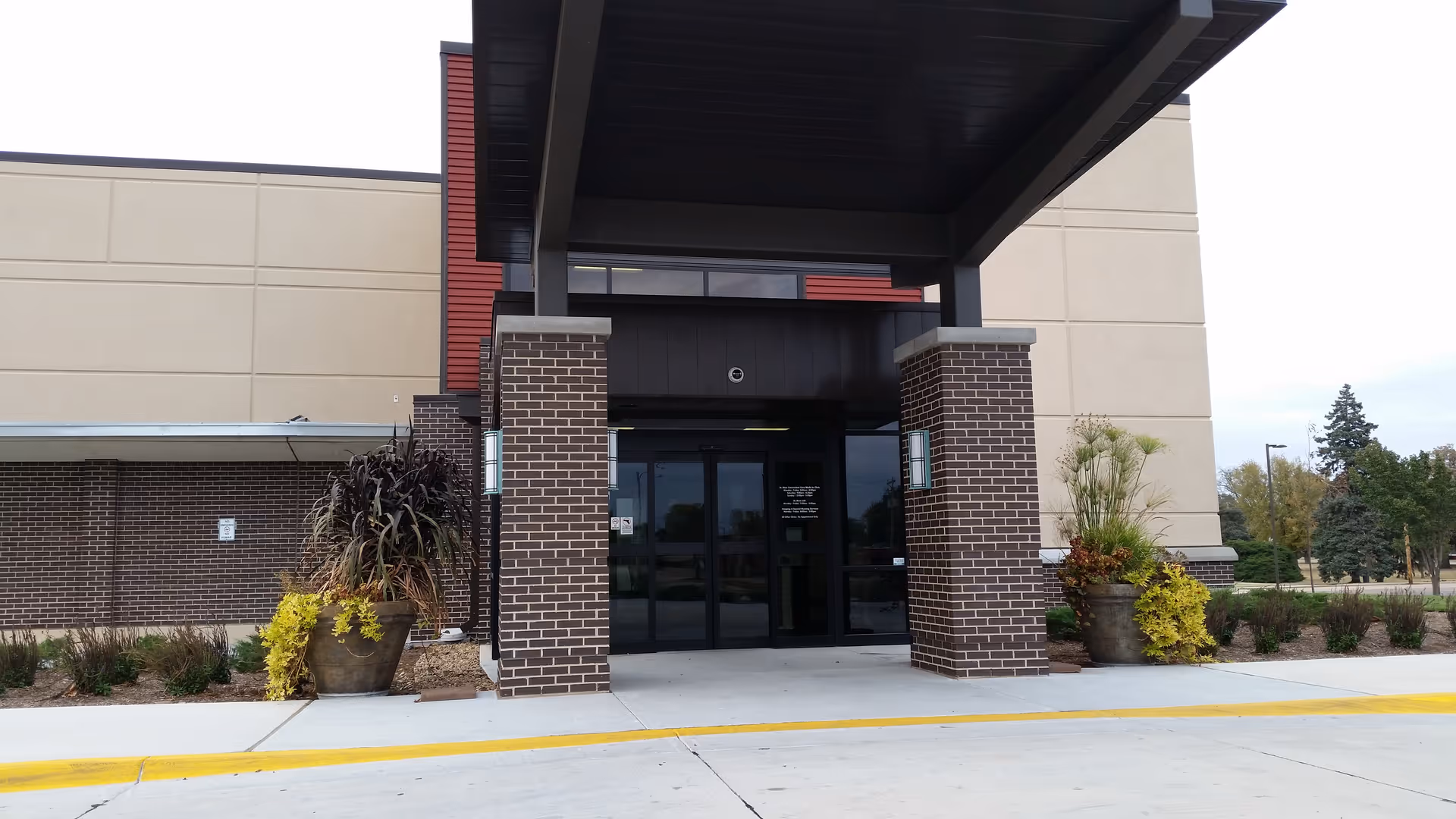 Front entrance of St. Rose Health Center with brick columns, glass doors, and potted plants.