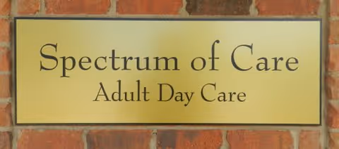 Yellow sign on brick wall reads Spectrum of Care Adult Day Care.