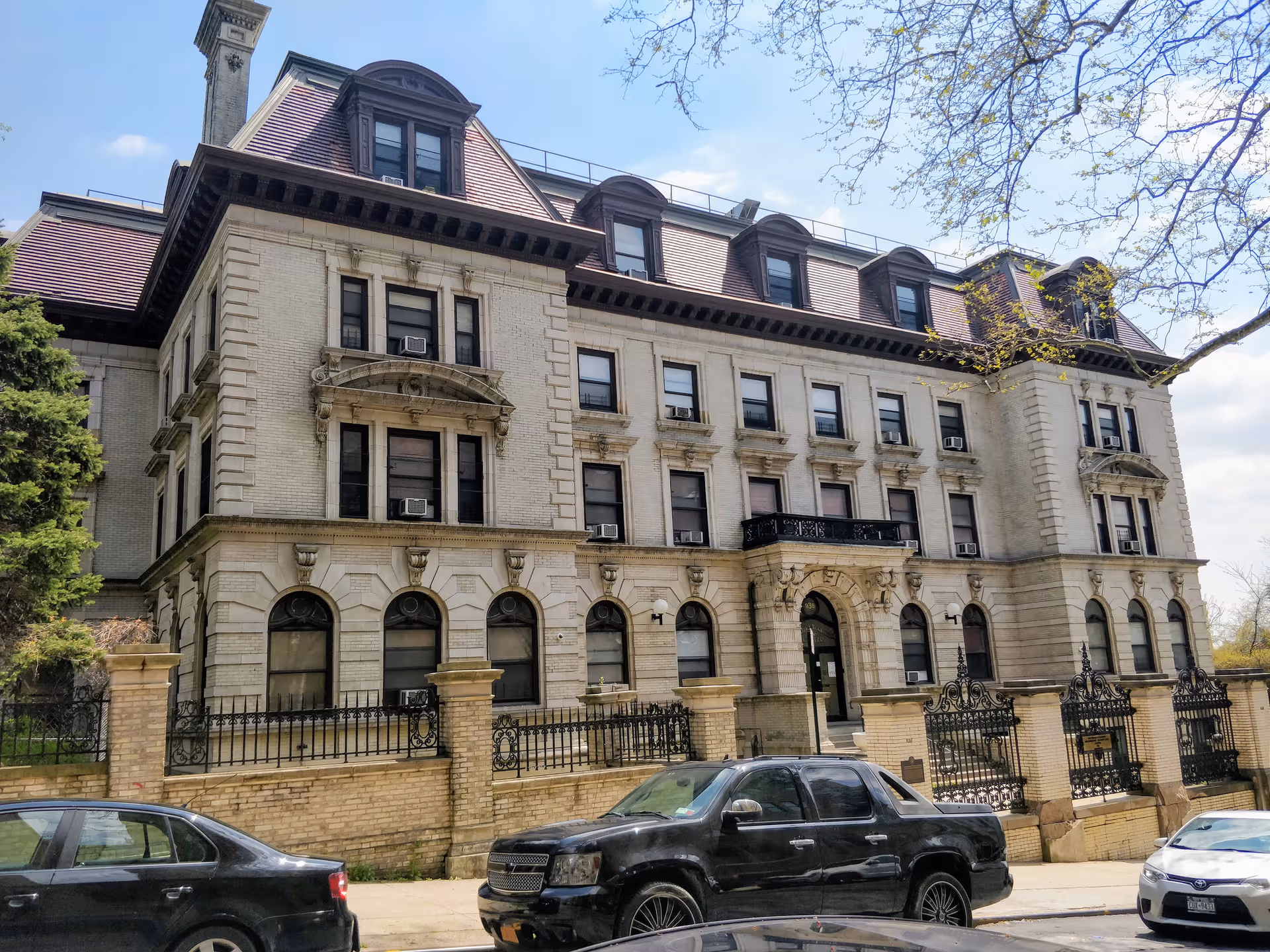 A large historic brick building with arched windows and a gated front entrance.