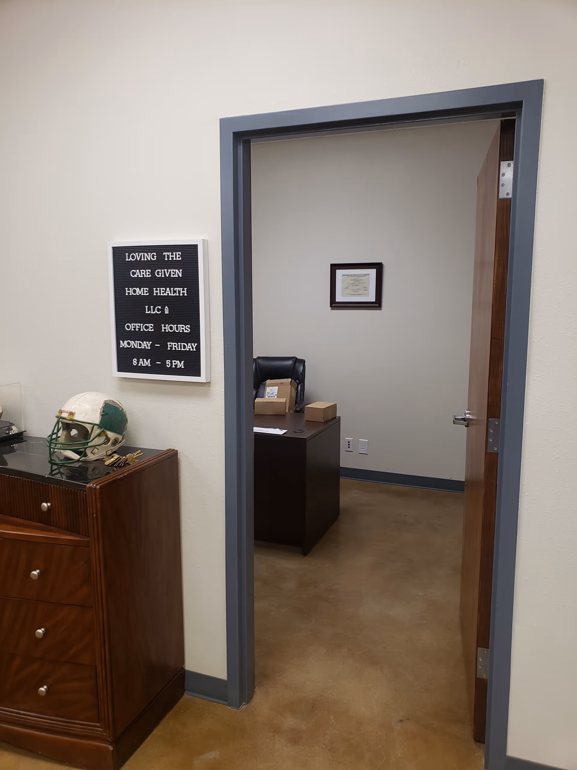 Interior office space with desk, certificate on wall, and signboard near a doorway.