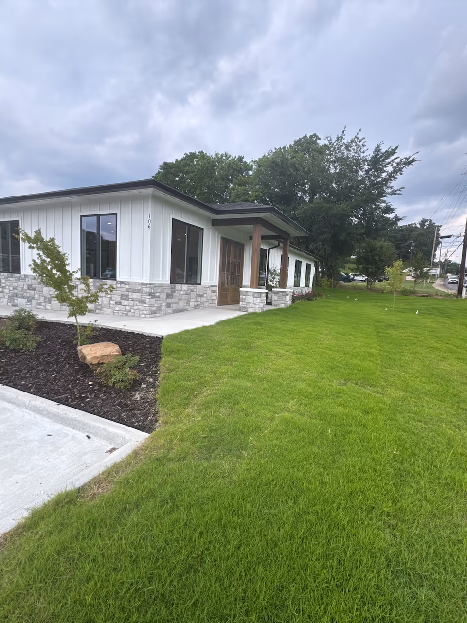 Single-story facility with white siding, stone accents, and a manicured lawn by the entrance.