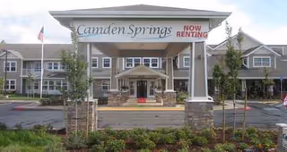 Front view of Camden Springs senior living facility with entrance sign and landscaping.