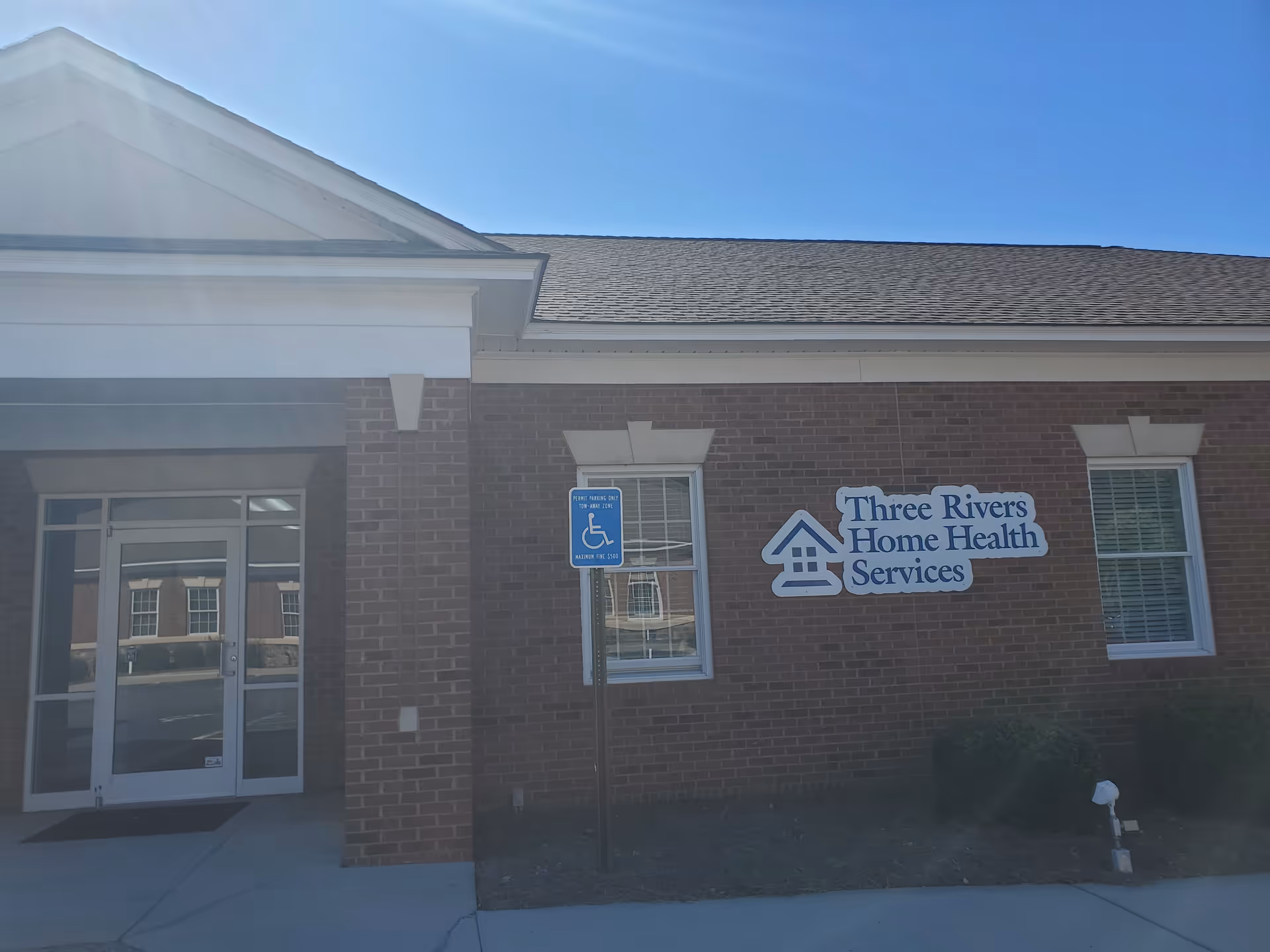 Brick building exterior with a Three Rivers Home Health Services sign and a handicapped parking sign.
