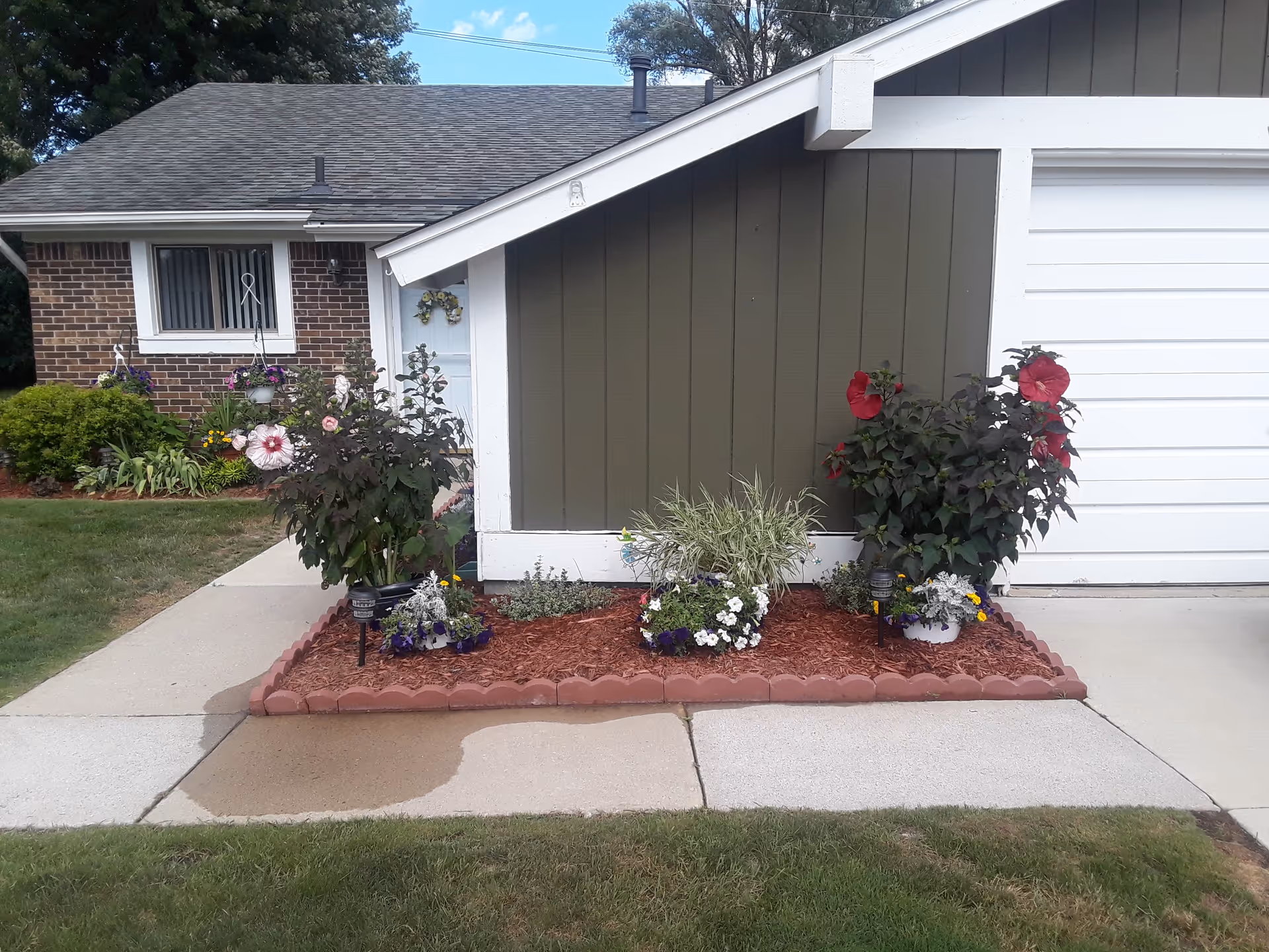 Front view of a single-story building entrance with flowering planters and a walkway.
