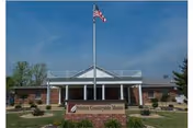 Front view of Aviston Countryside Manor with flagpole, brick exterior, and welcoming entrance.