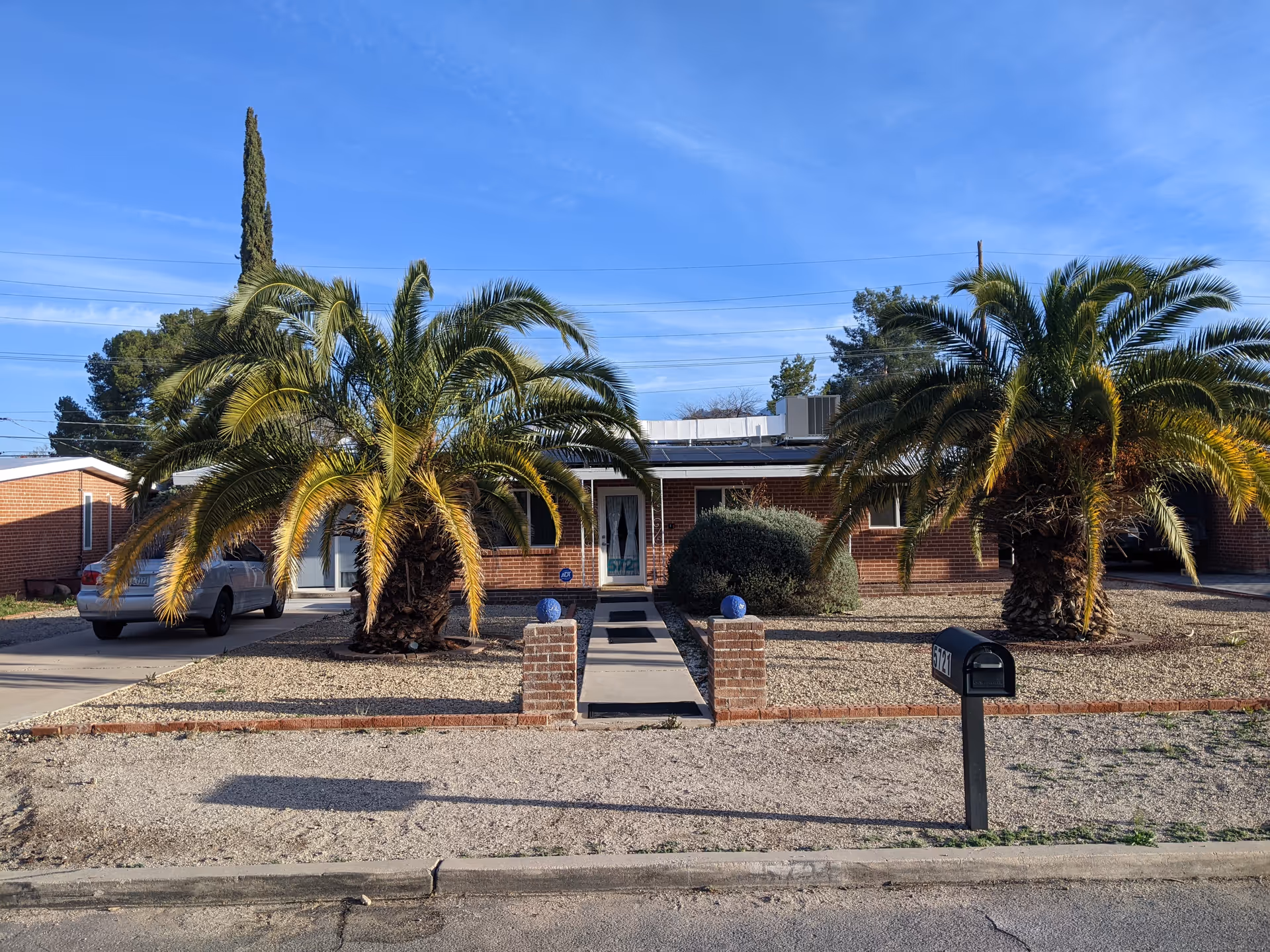 Front exterior of Elim Palmtrees Assisted Living Home with palm trees and driveway.
