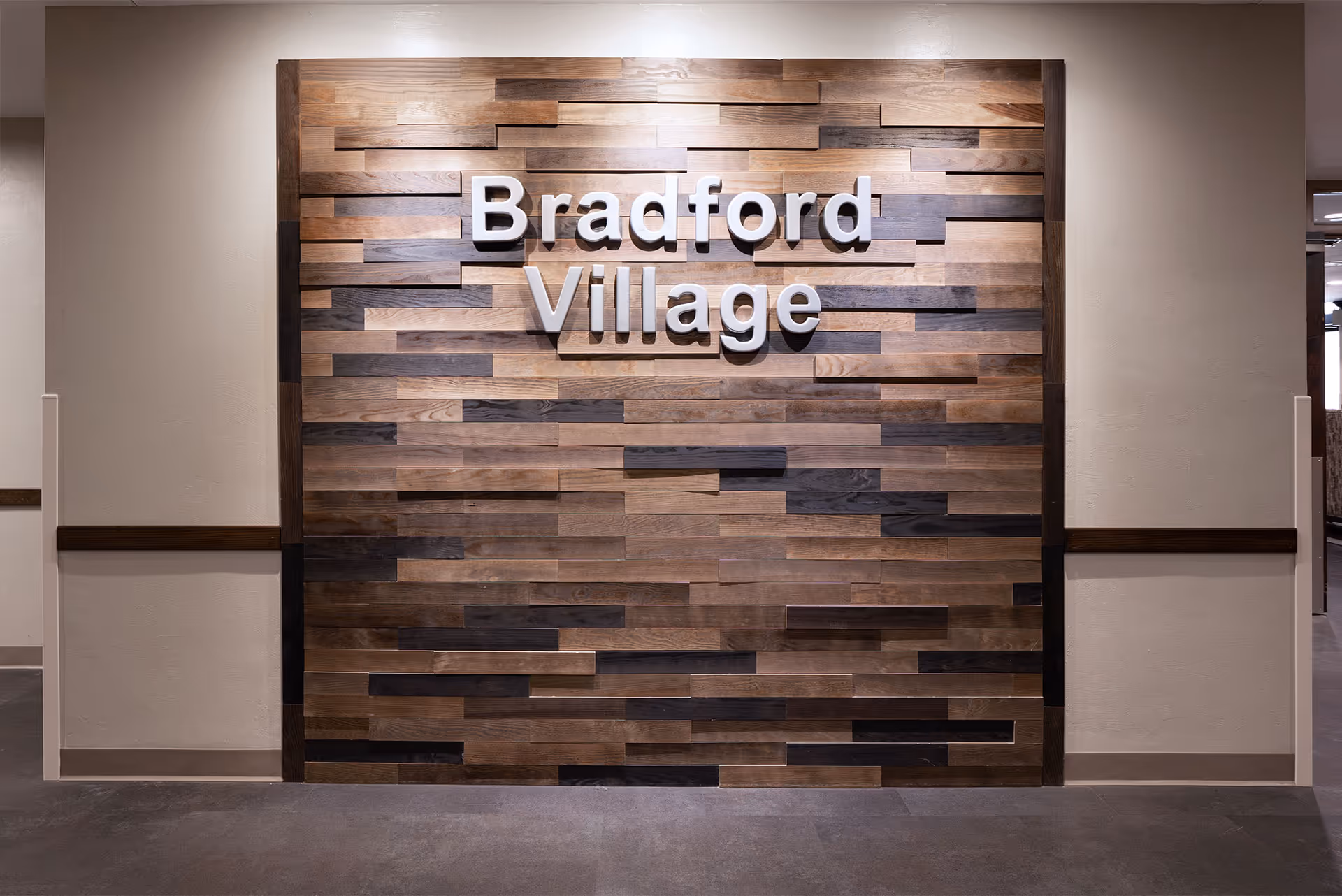 Interior wall with a decorative wooden panel featuring the text 'Bradford Village' in large white letters.